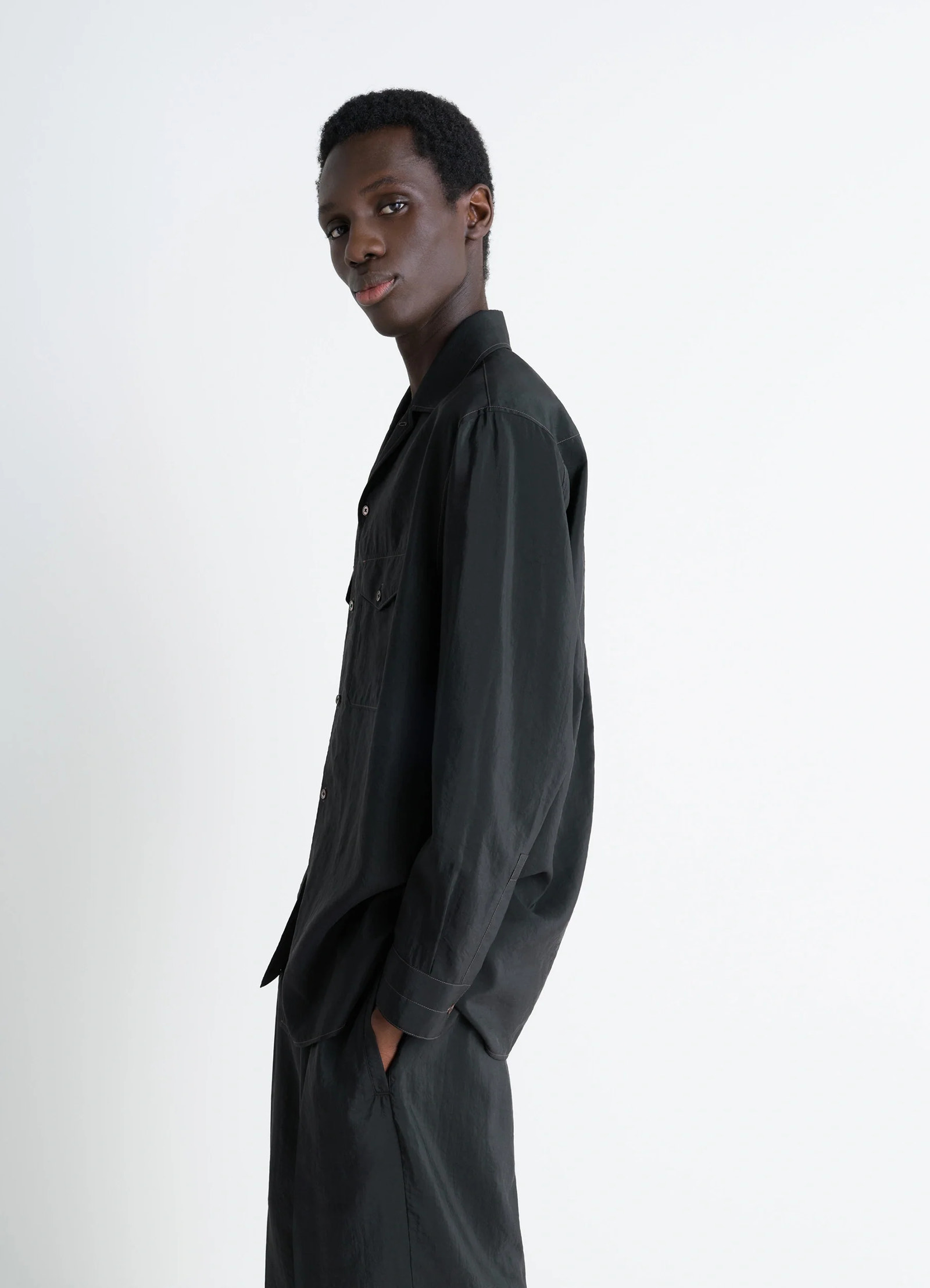Lemaire convertible collar shirt in black dry silk blend, model shot, side view profile loose untucked sleeves