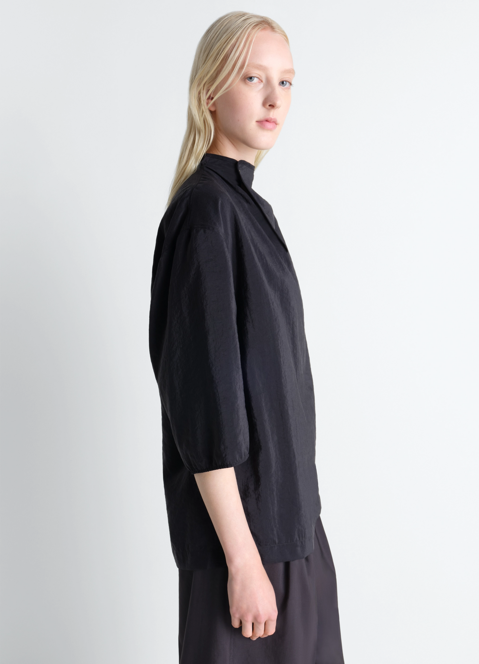 Soft collar top in dry silk in black dry silk, model shot, three-quarter view loose fit cropped sleeves
