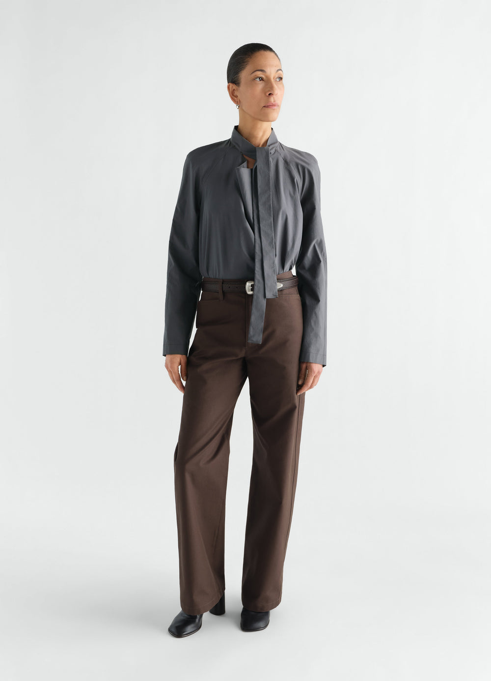 Ascot blouse in washed cotton silk dark grey worn by a model with brown trousers LEMAIRE