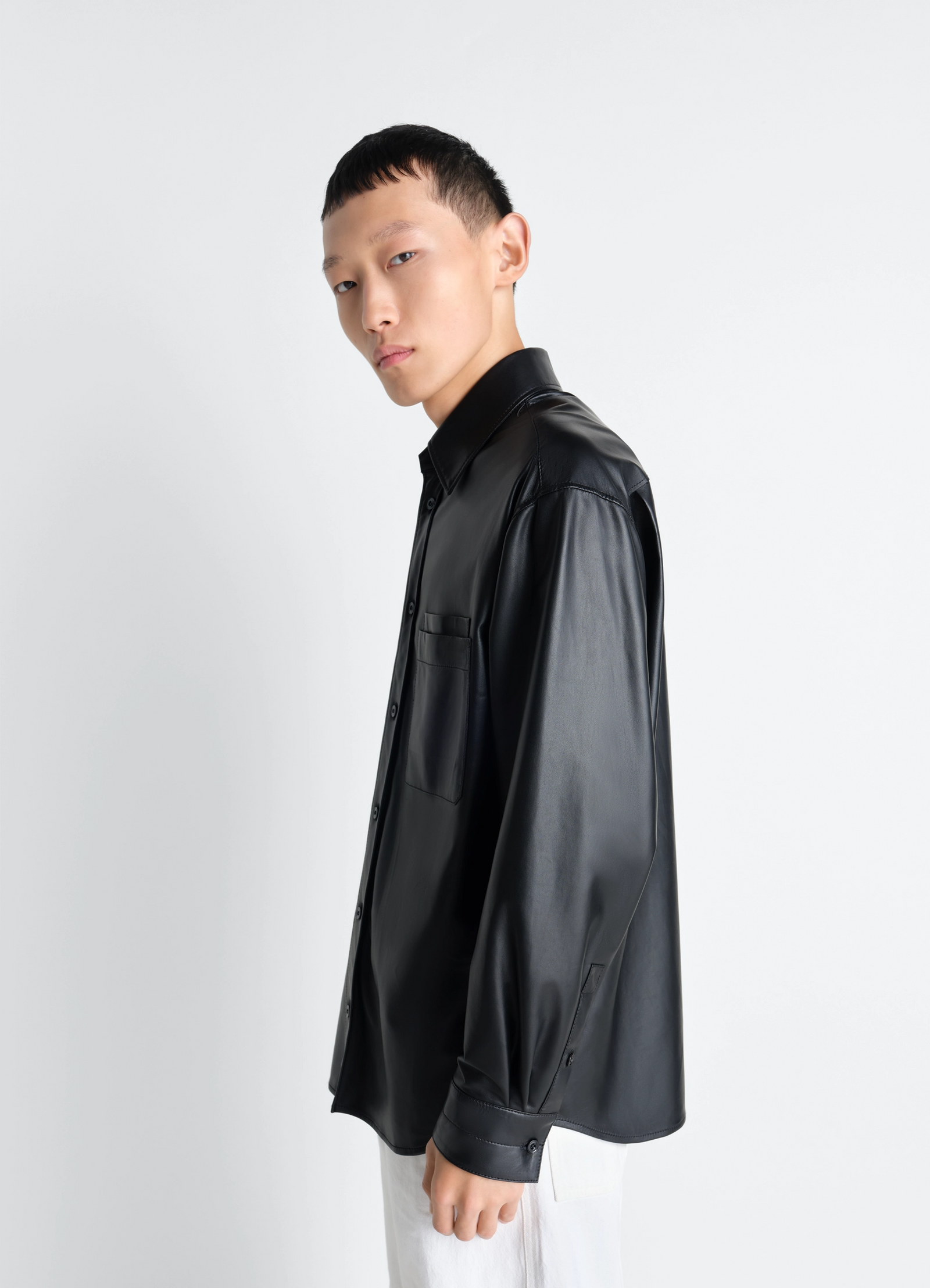 Overshirt in light nappa lamb in black lamb nappa leather, model shot, side view upper body sleek button cuffs