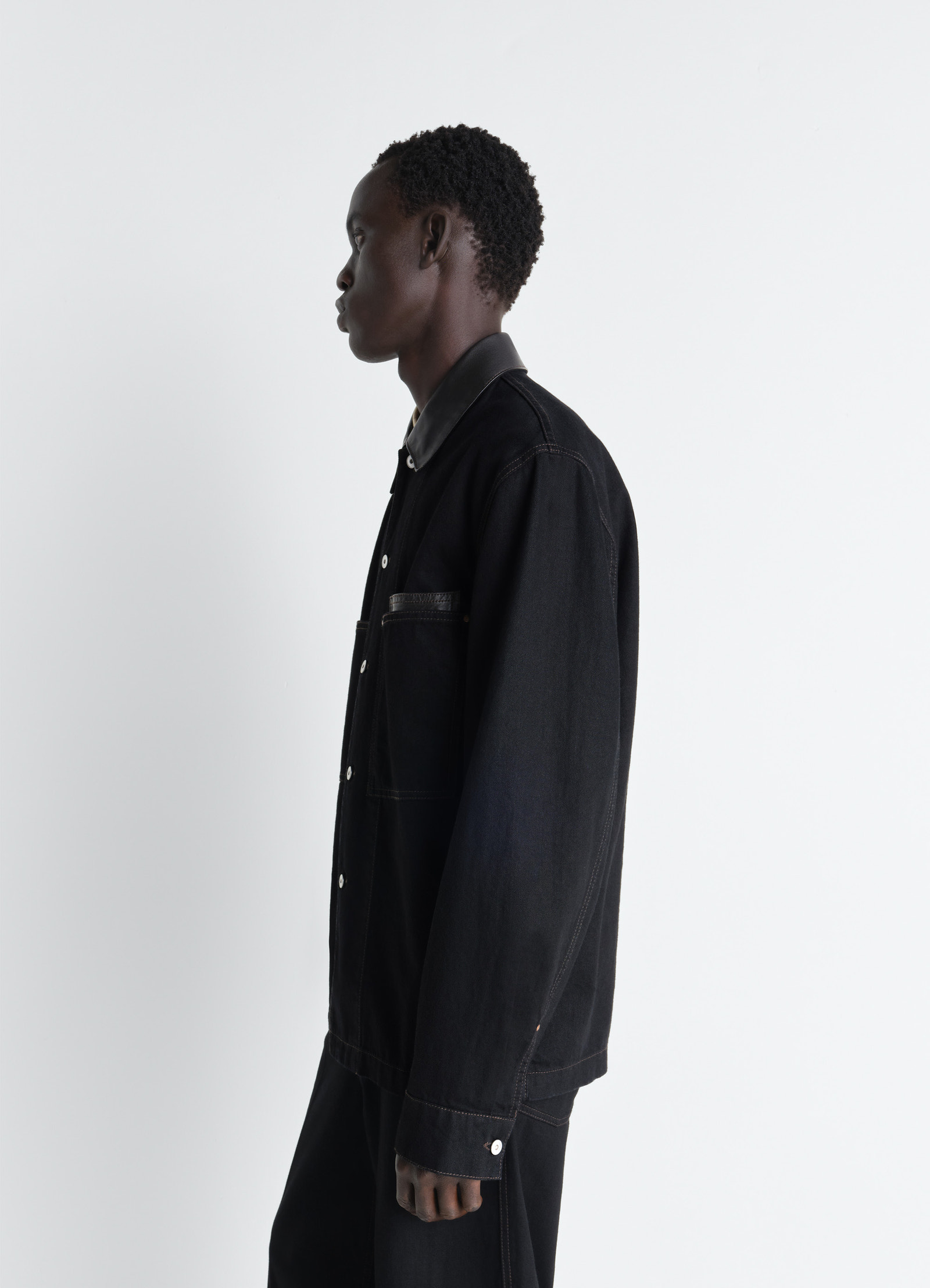 Workwear overshirt with leather col in black denim and leather, model shot, profile view leather collar detail