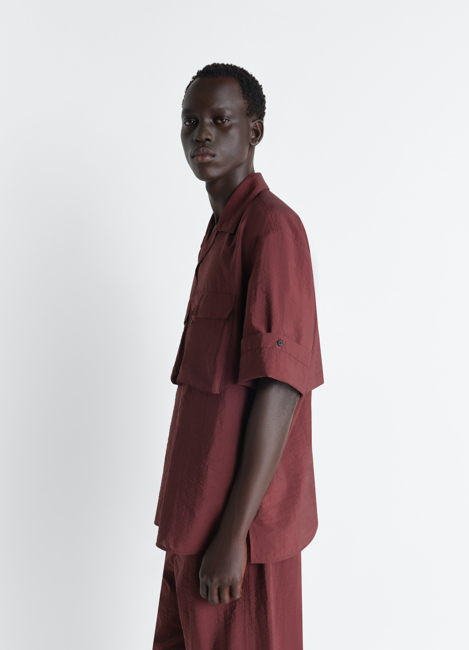 Short sleeve utility shirt in washed technical cotton, model shot, three-quarter rear view buttoned tab sleeves