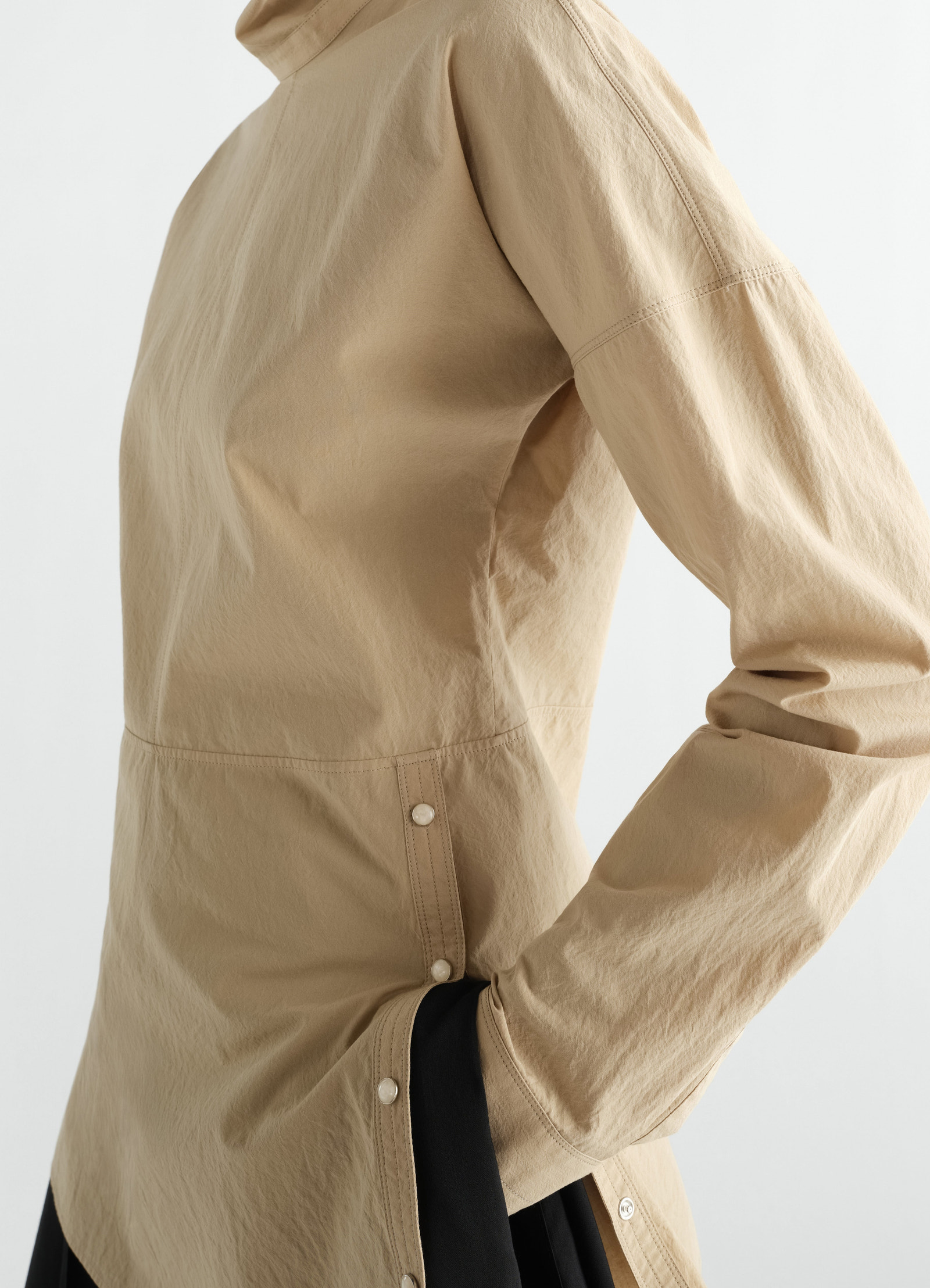 Press-stud beige cotton crepe bib top by lemaire worn by model side view with sleeve detail and black skirt visible