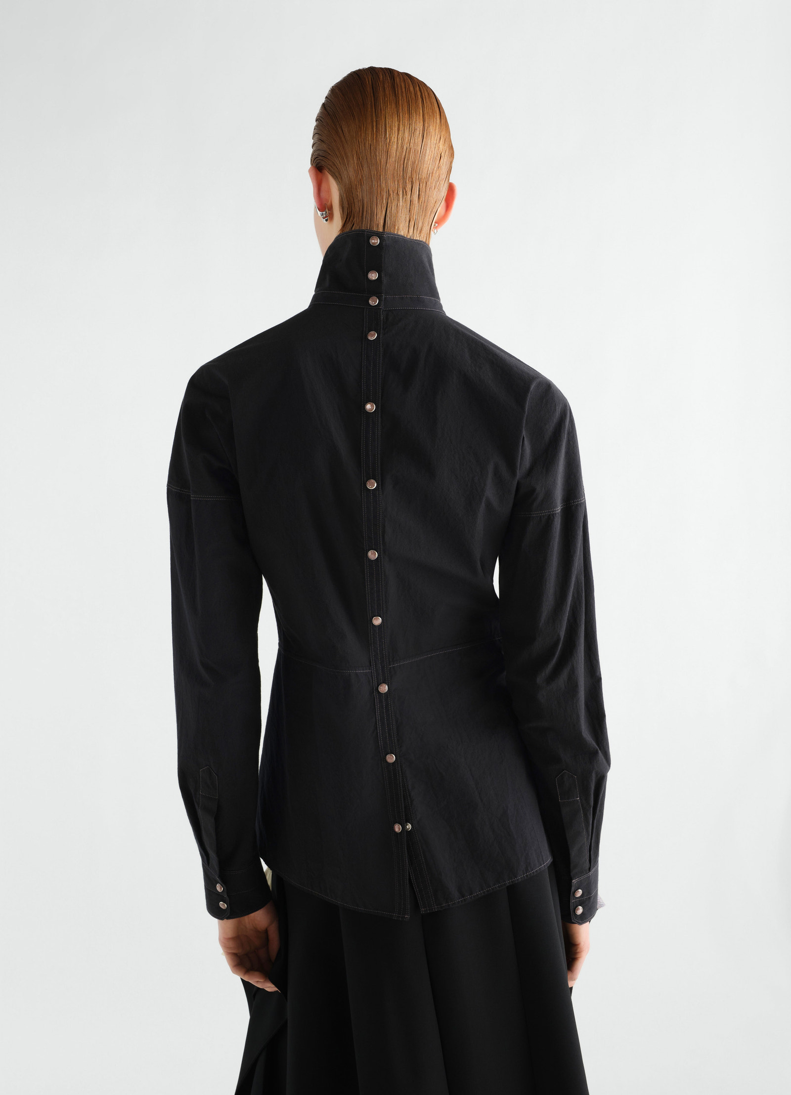 Press-stud black cotton crepe bib top by lemaire, back view worn by a model with high collar and button details.
