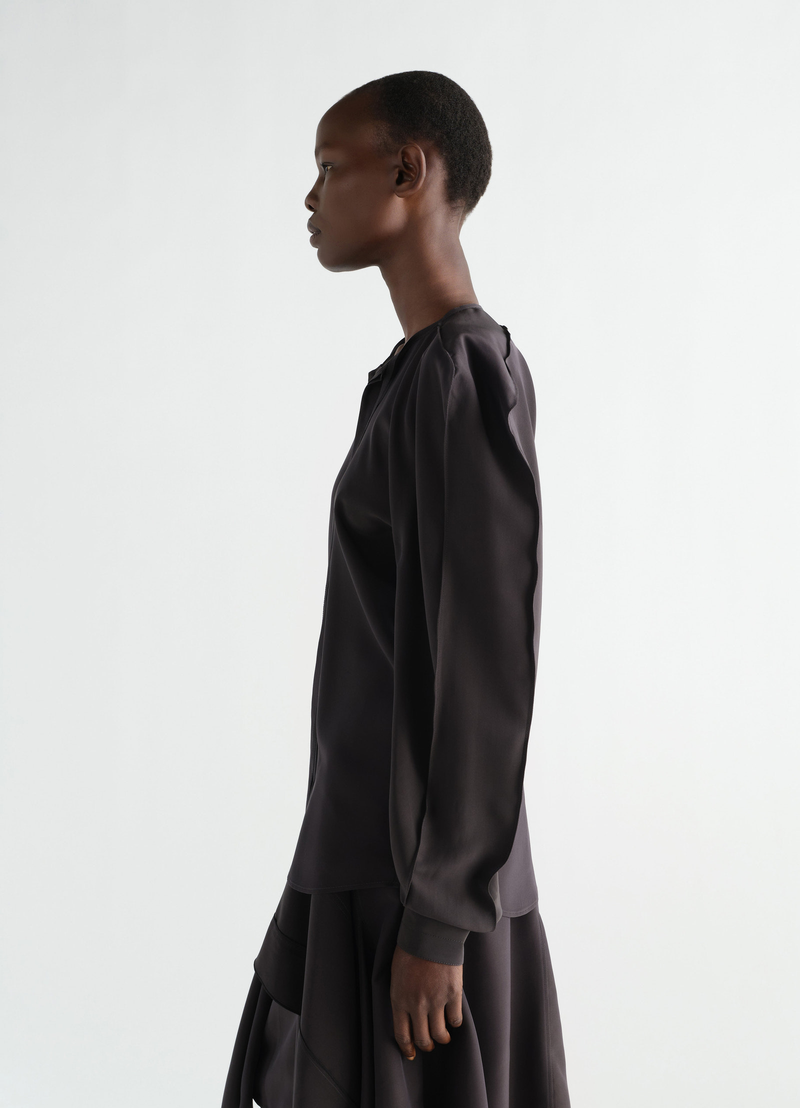 Layered black silk and viscose blouse by lemaire worn by model side view on white background