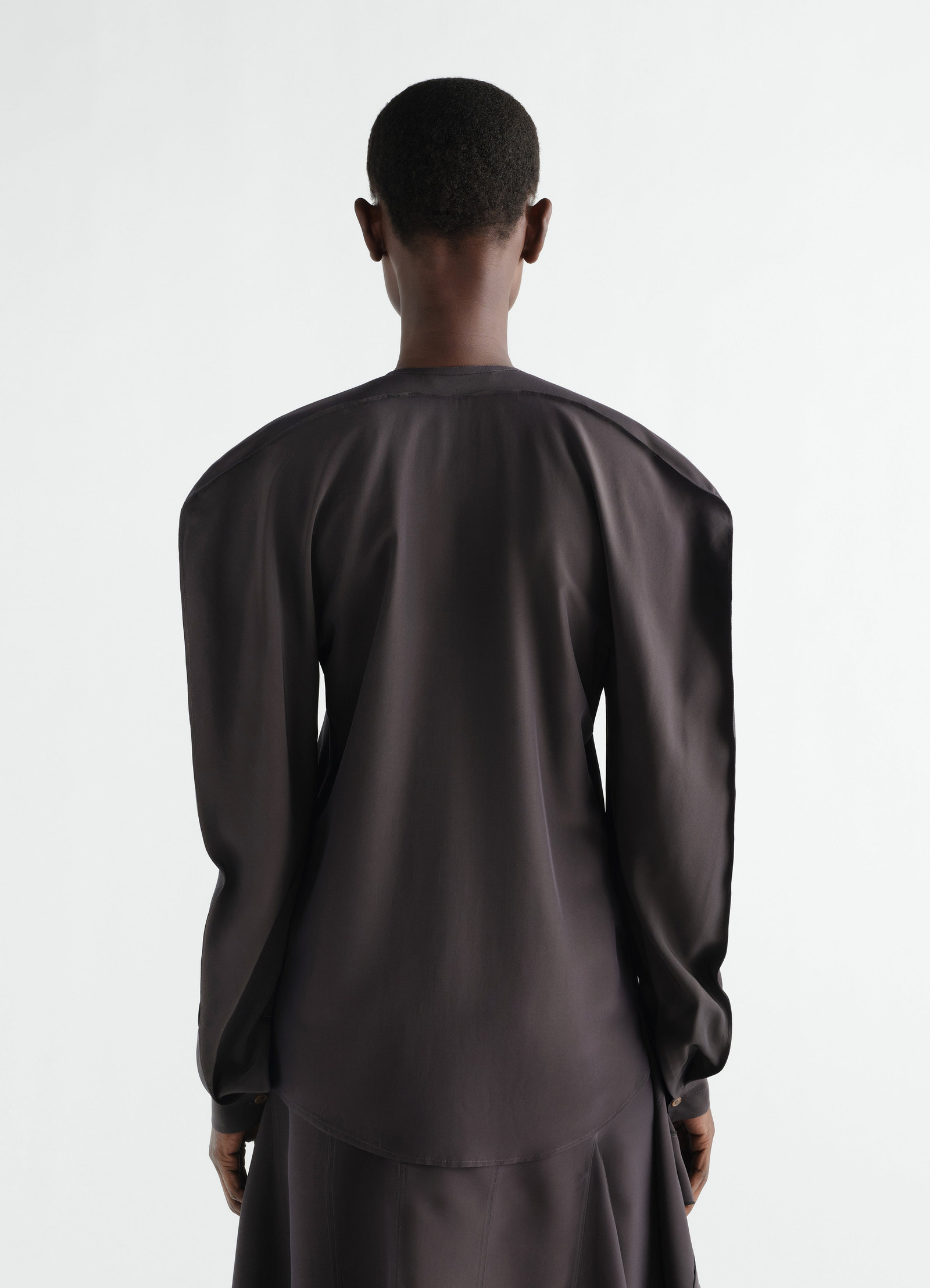 Layered silk and viscose black blouse by lemaire worn by model back view with long sleeves and button cuffs