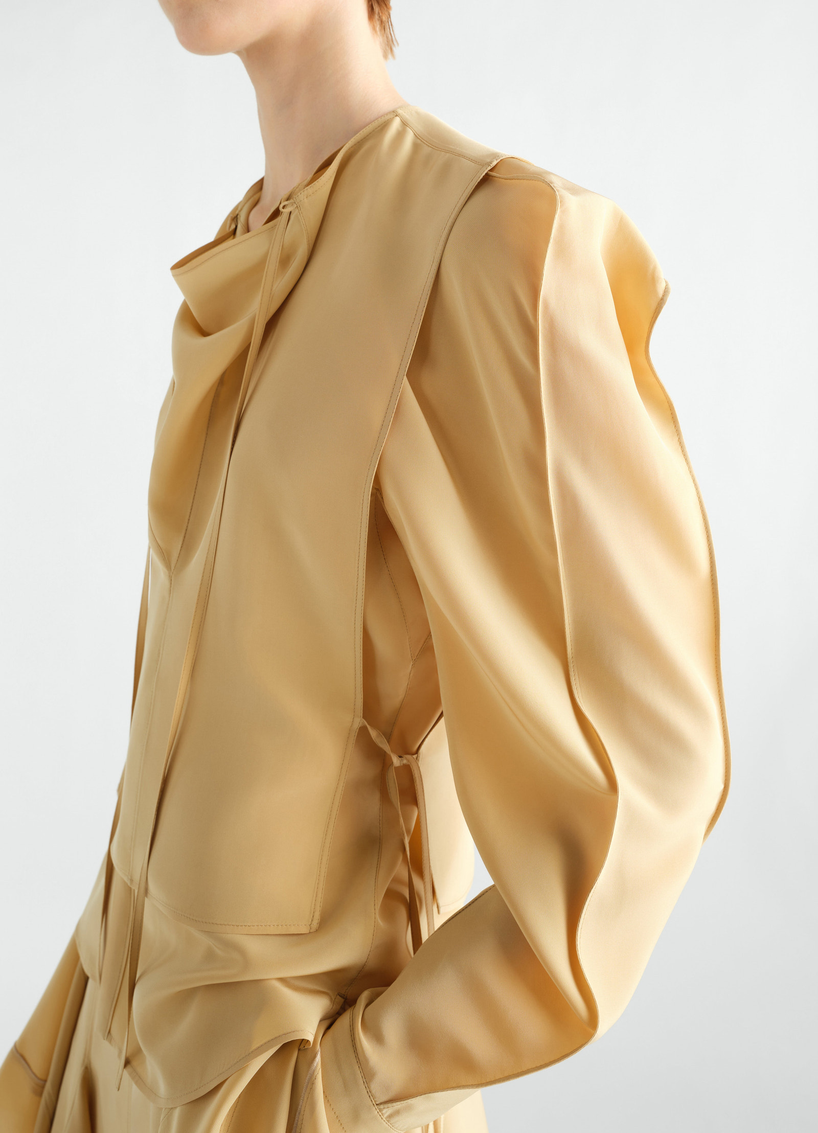 Layered beige silk and viscose blouse by lemaire worn by model side view with draped details and long sleeves