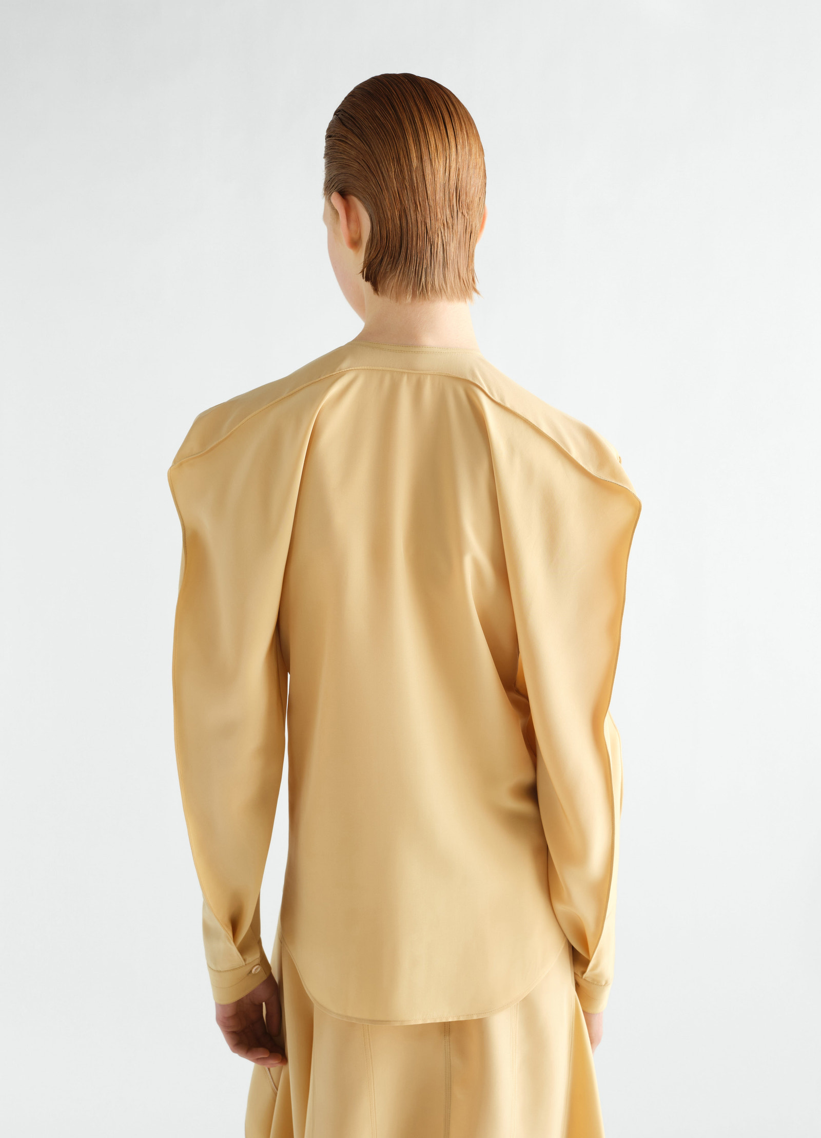 Layered silk and viscose cloth blouse in beige by lemaire worn by a model, back view with structured shoulders