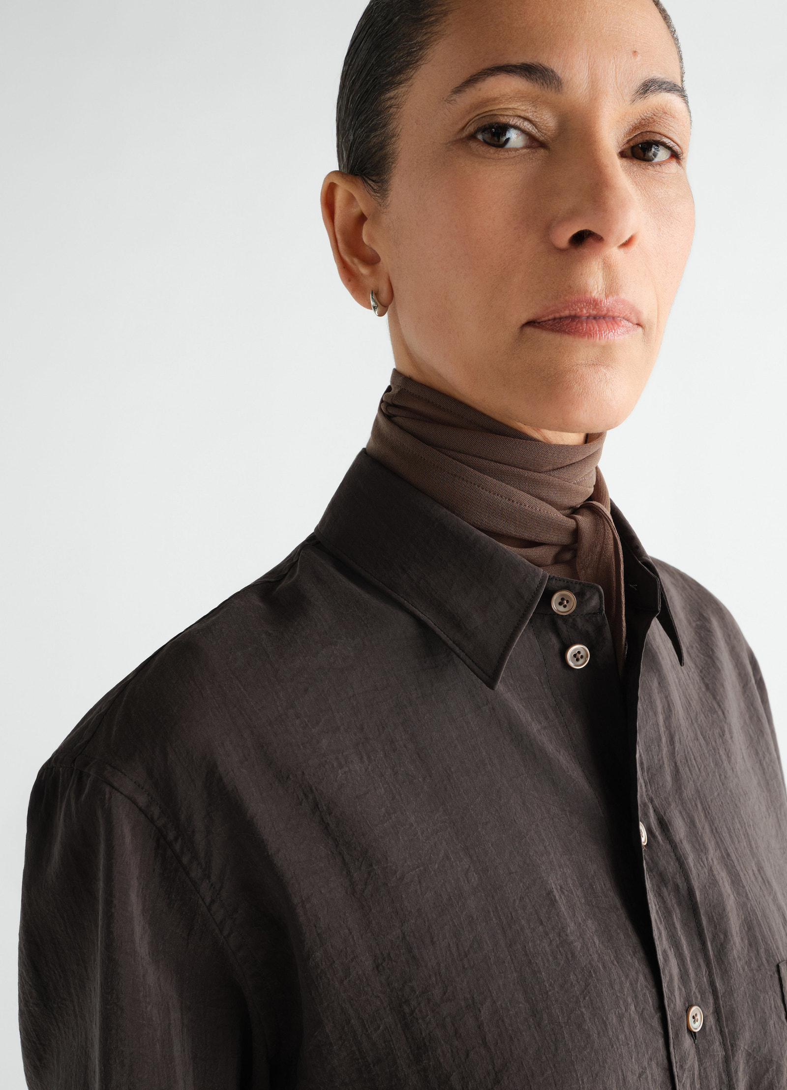 Straight dry silk brown shirt by lemaire close-up worn by model with matching neck scarf on white background