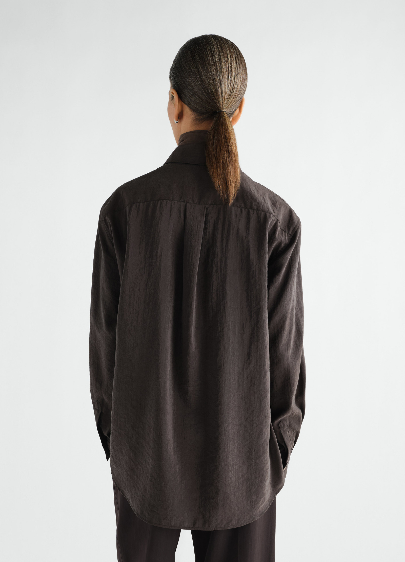 Straight shirt in dark brown dry silk by lemaire worn by model back view with long sleeves and curved hem