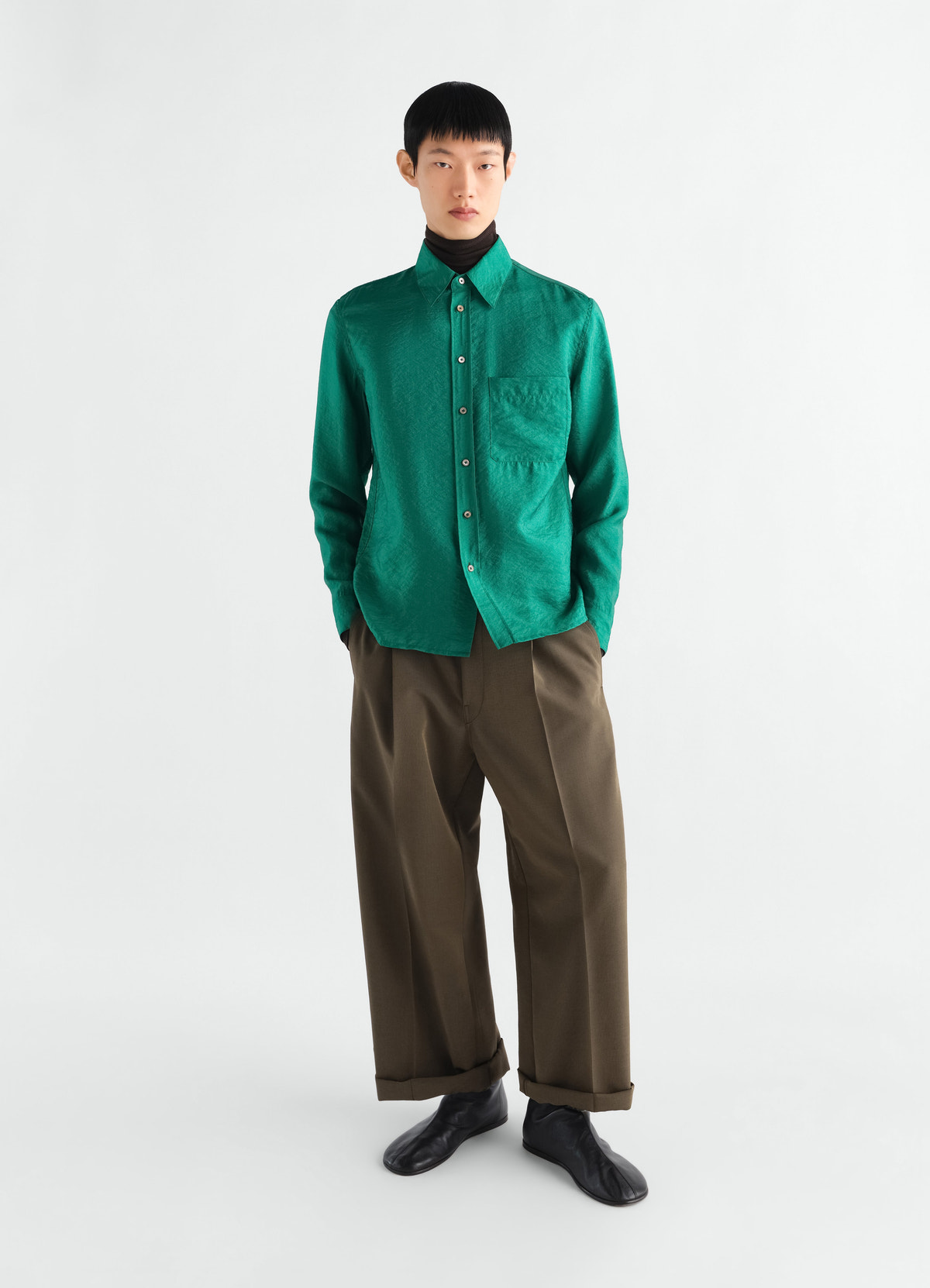 Fitted green shiny cupro shirt by lemaire worn by model with brown trousers on white background