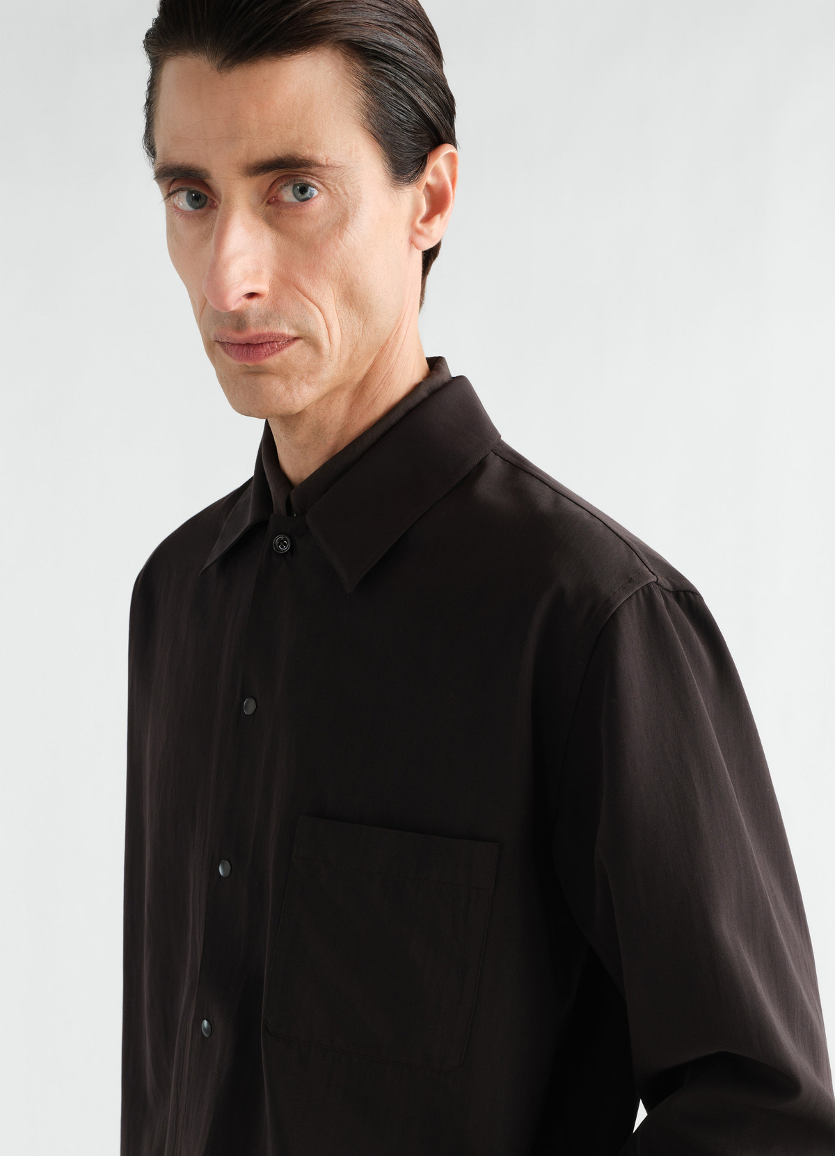 Light black wool gabardine overshirt by lemaire worn by model showing front and pocket detail