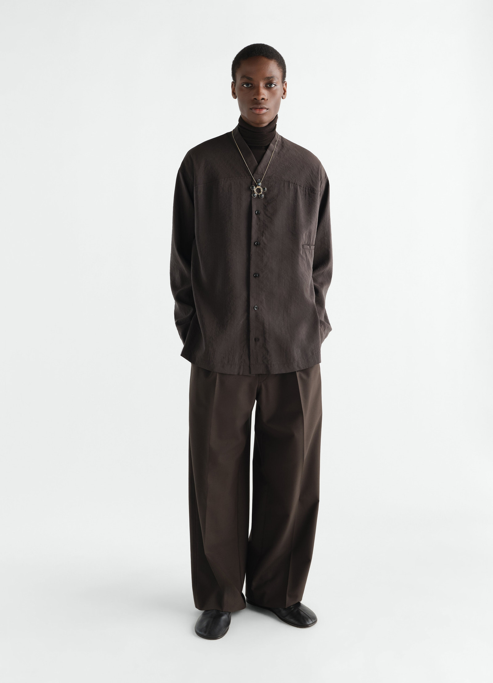 V-neck dry silk shirt in dark brown worn by model with matching wide trousers lemaire front view