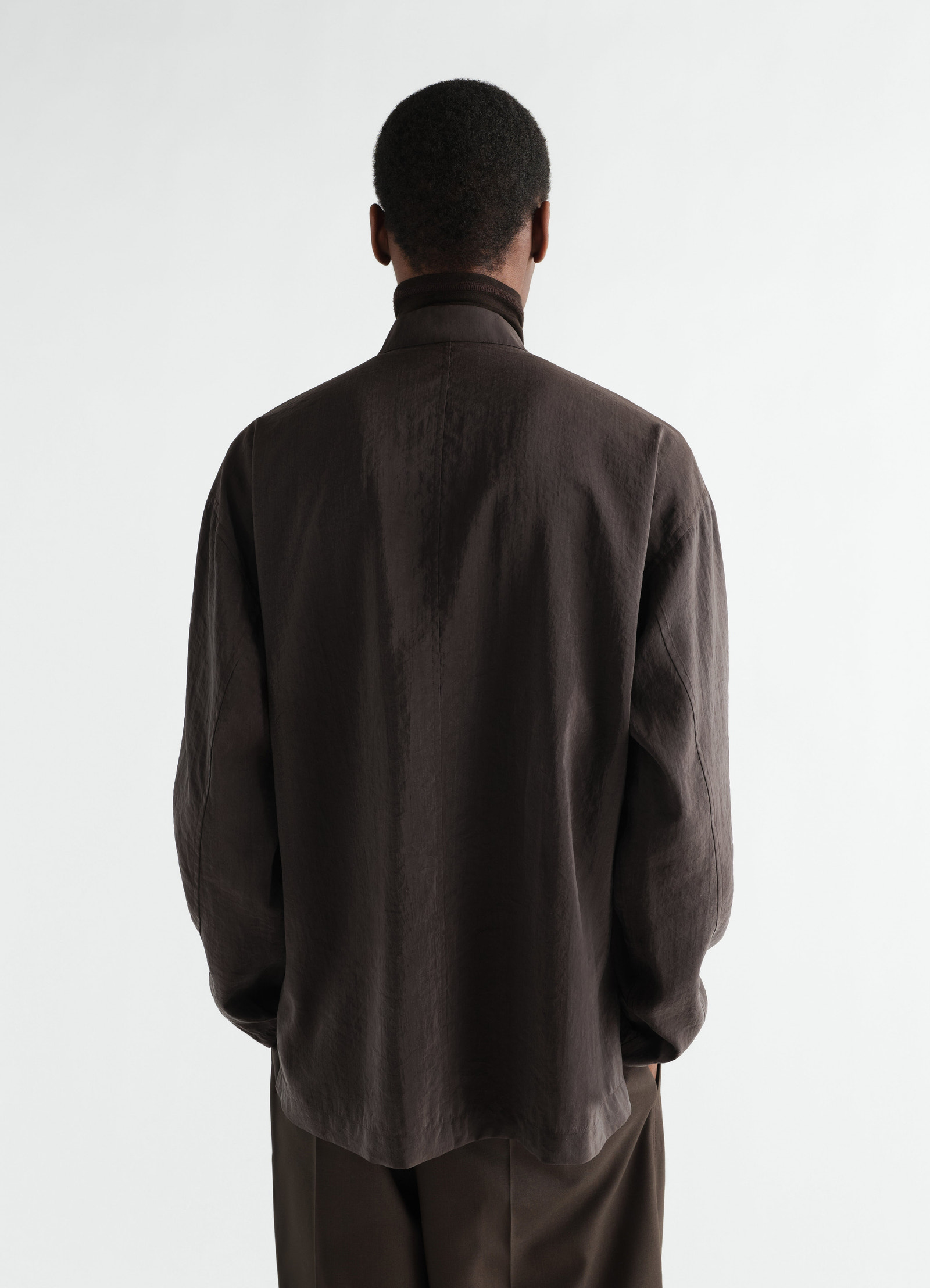 V-neck dry silk shirt in dark brown by lemaire worn by a model shown from the back on white background