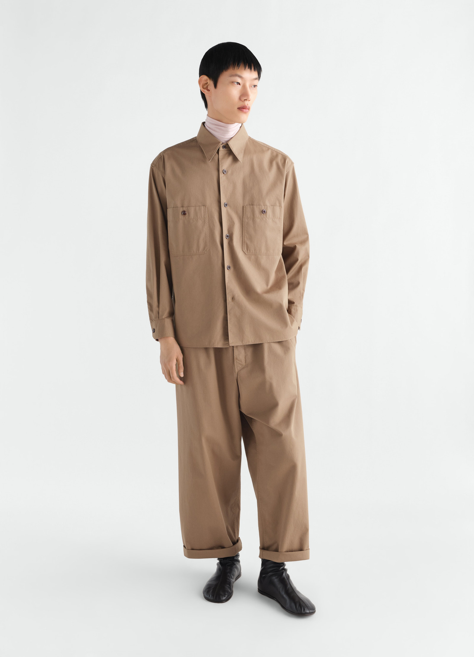 Two-pocket light brown cotton twill shirt lemaire worn by model front view with matching trousers and black shoes