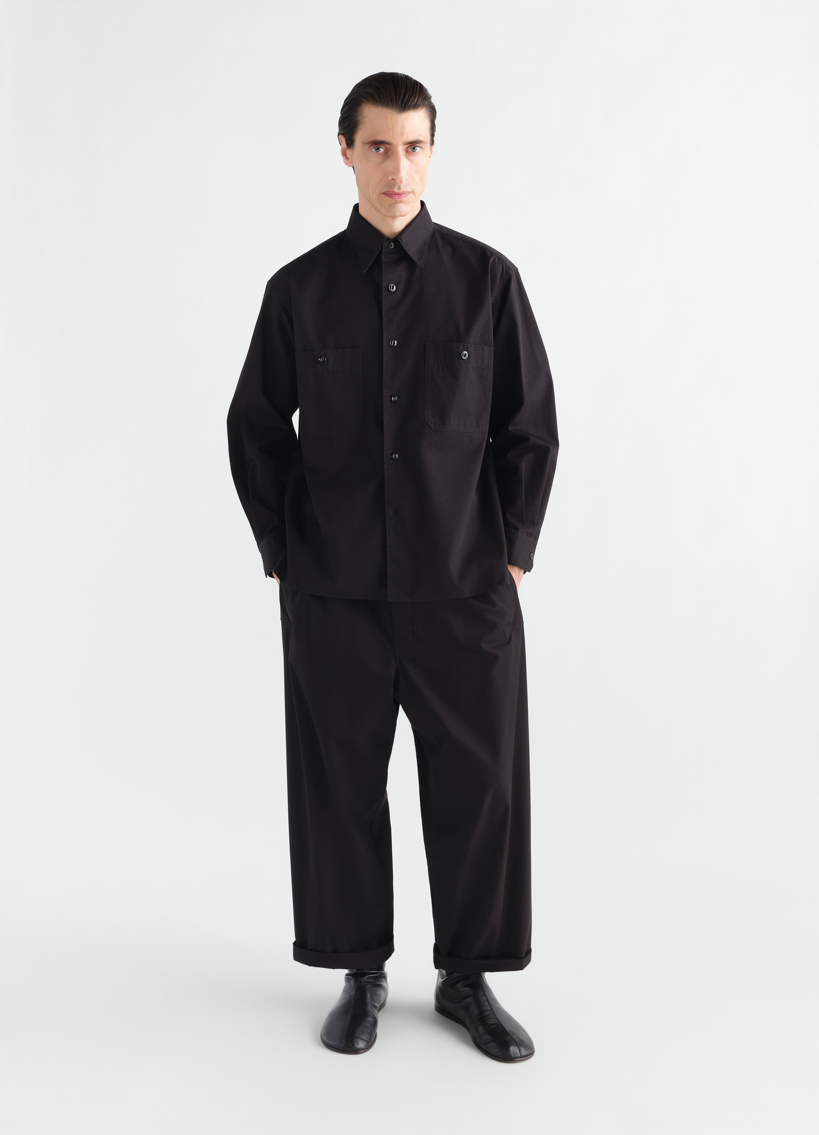 Two-pocket black cotton twill shirt and wide pants worn by model in full front view lemaire