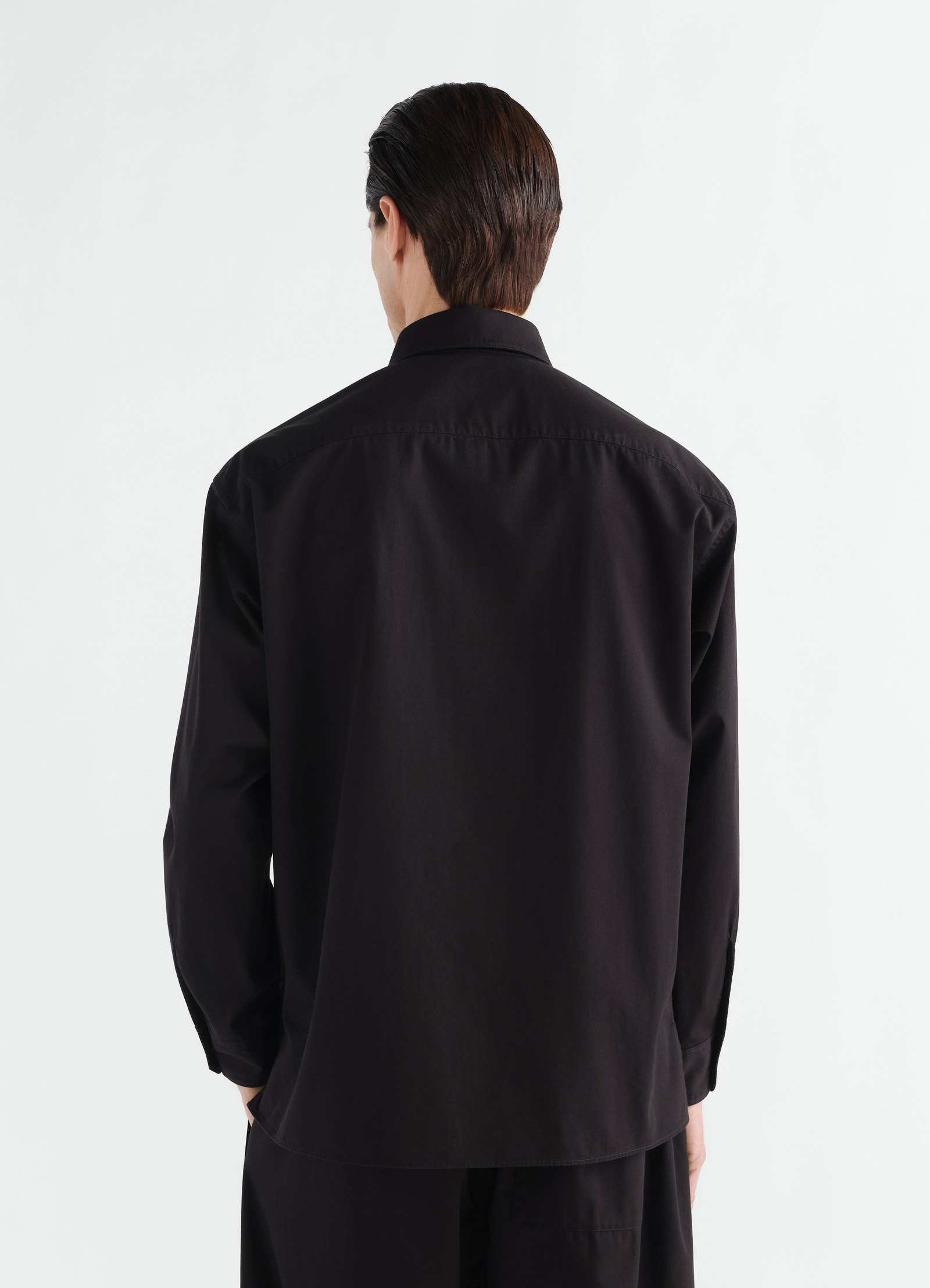 Two-pocket black cotton twill shirt by lemaire worn by a model back view long sleeves collar