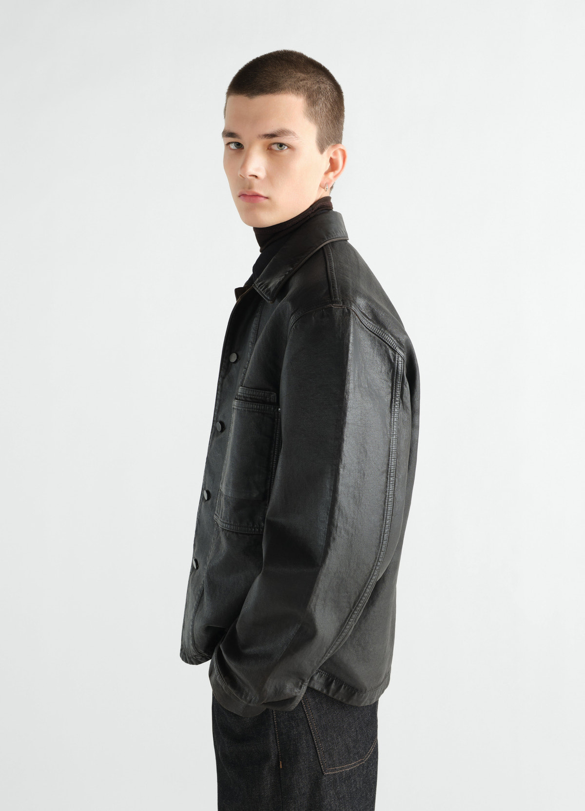 Workwear overshirt in black coated denim with buttons worn by model side view lemaire
