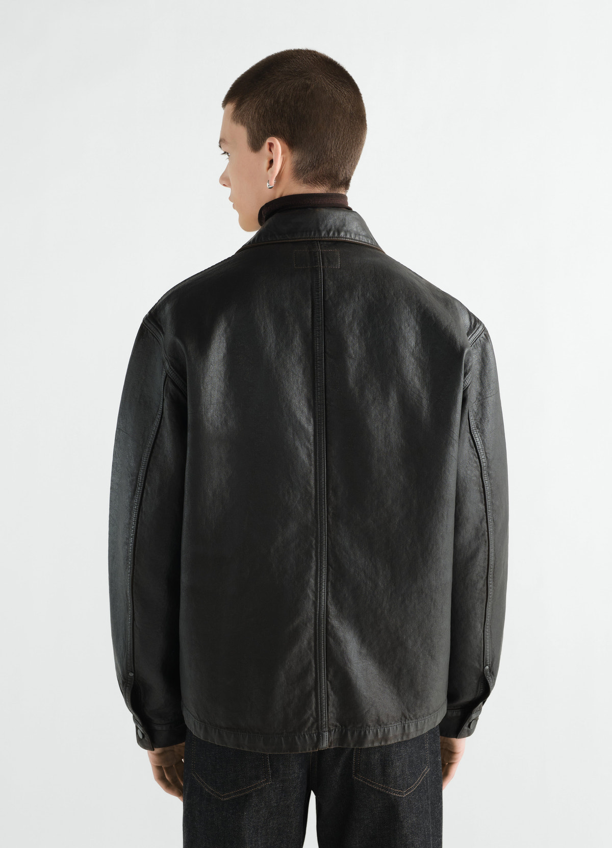 Black coated denim workwear overshirt lemaire back view worn by model with dark denim jeans