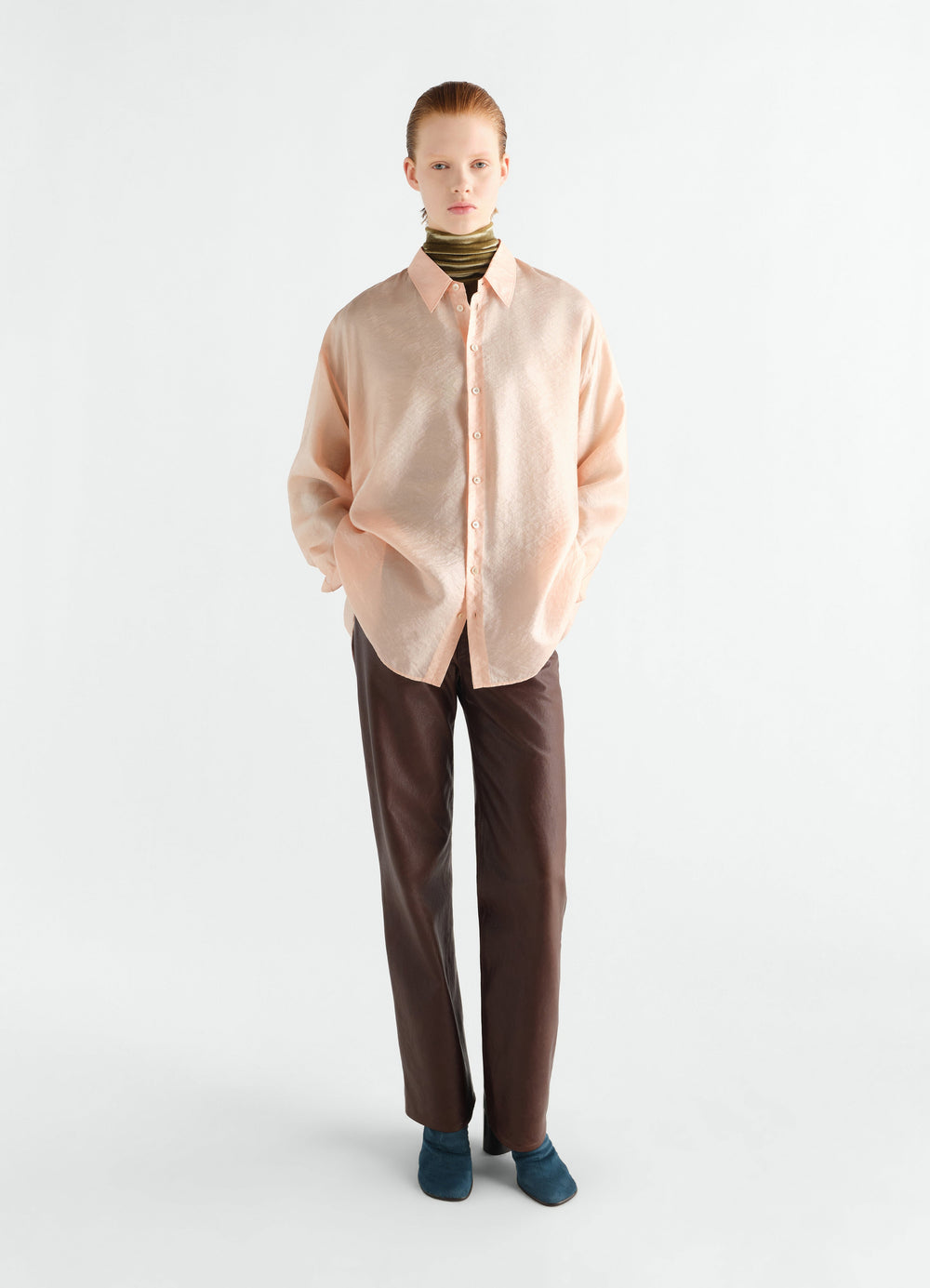 Draped shiny peach cupro shirt with collar worn by a model with brown trousers and blue shoes LEMAIRE front view