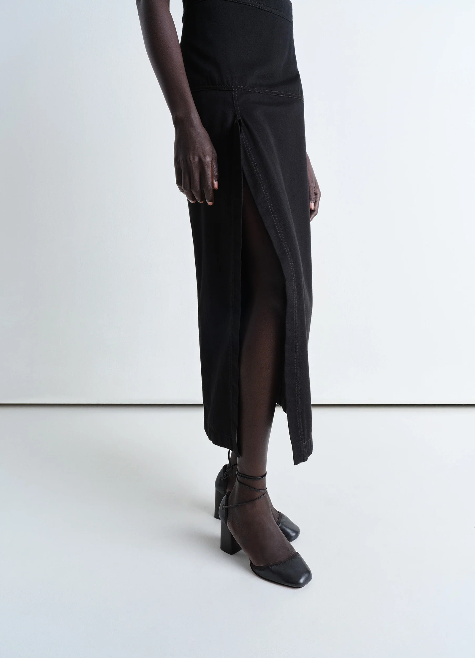 Lemaire asymmetrical wrap skirt in black cotton denim, model shot, side view asymmetrical hem