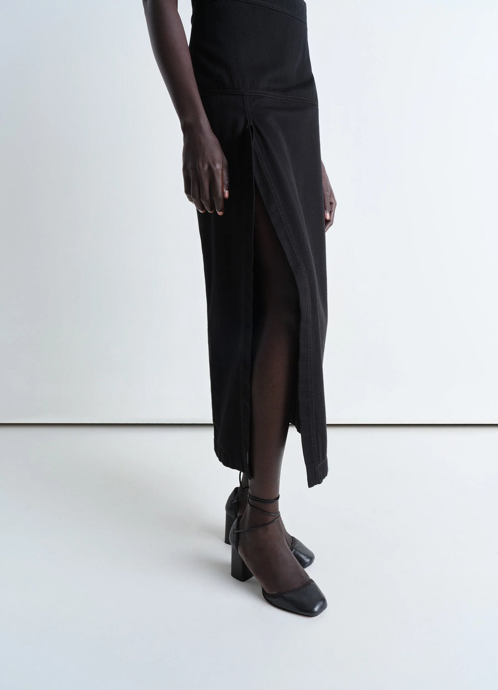 Lemaire Asymmetrical Wrap Skirt in Black Cotton Denim, model shot, side view asymmetrical hem