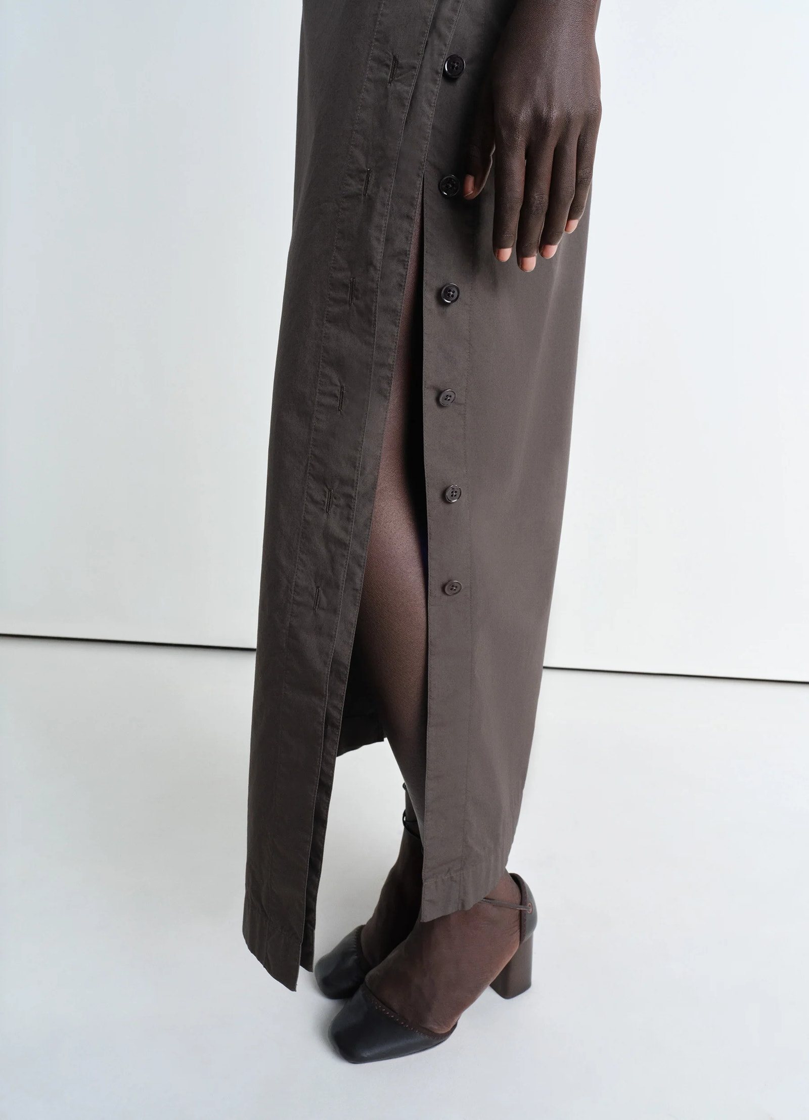 Lemaire buttoned long skirt in garment dyed cotton poplin, model shot, angled lower detail shot side slit with buttons