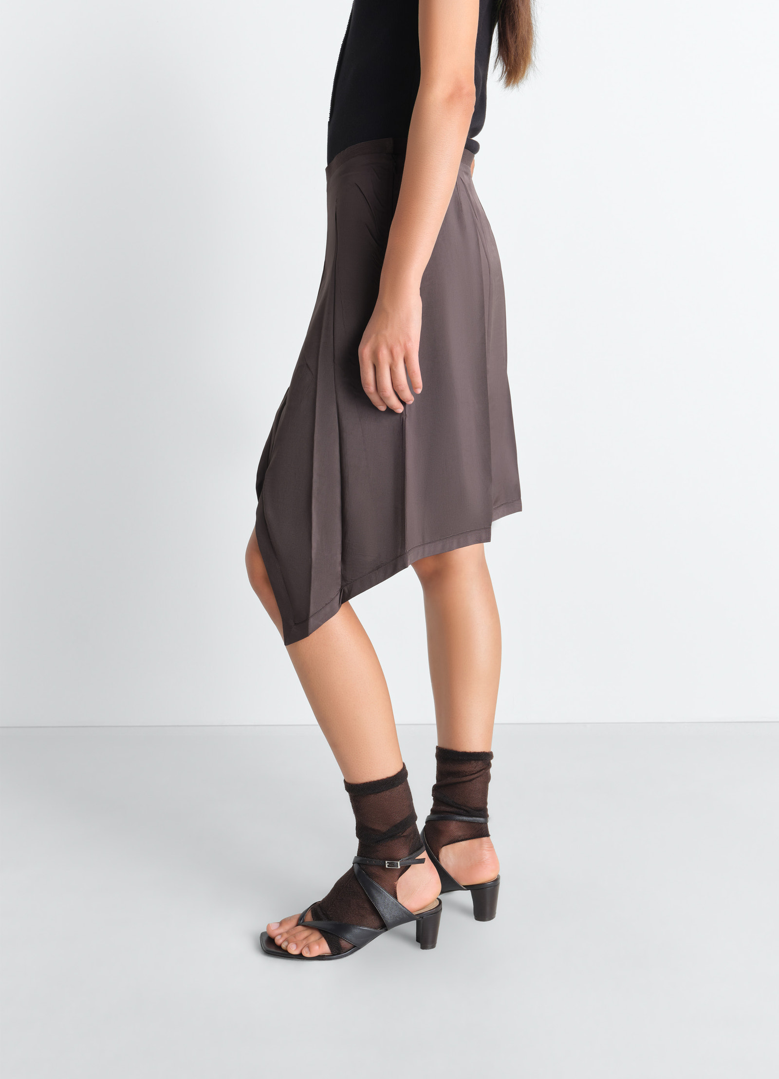 Creased foulard skirt in poly viscose twill, model shot, three-quarter view curved hem, side slit