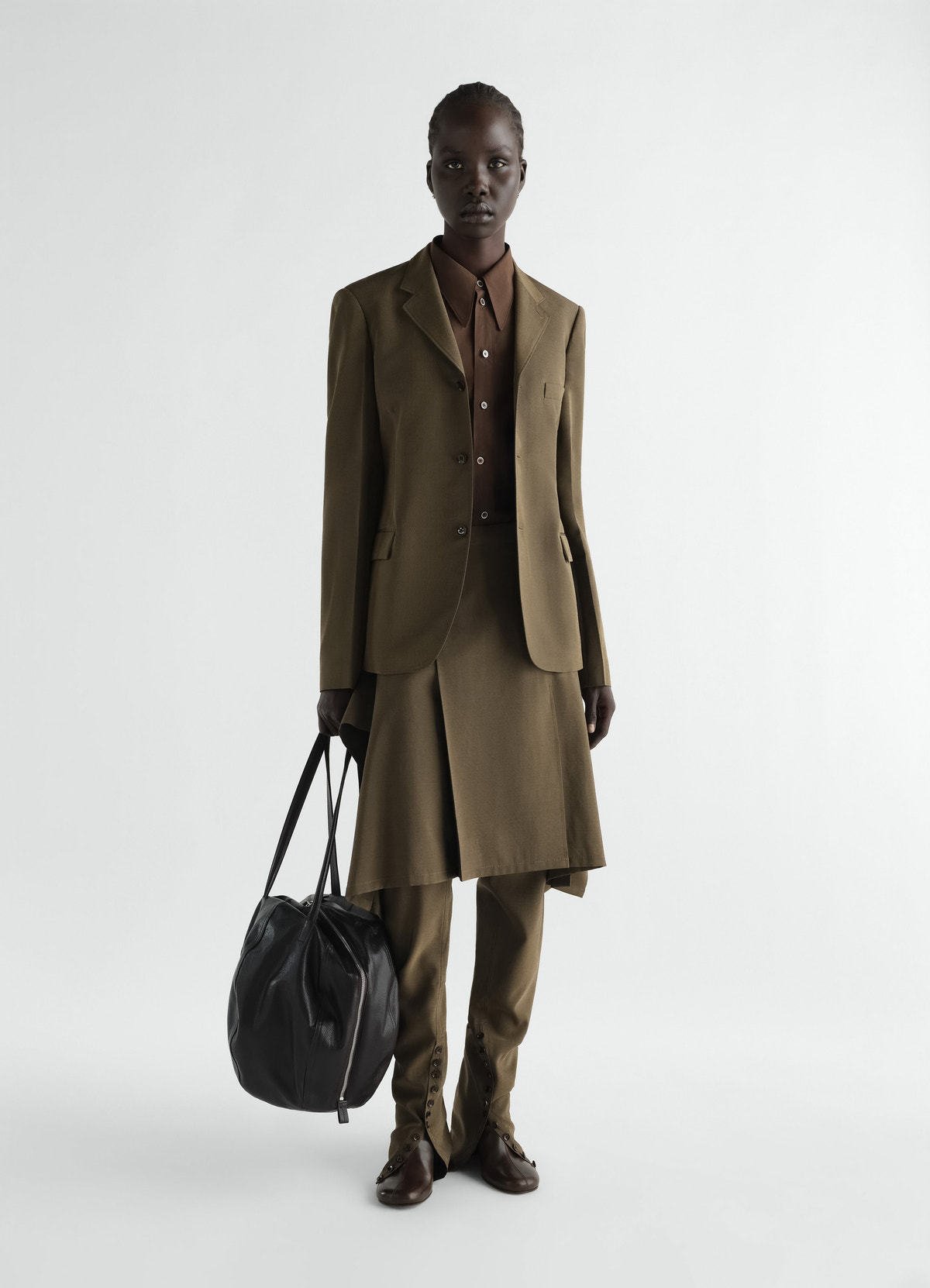 Pleated brown wool and mohair skirt with matching blazer and trousers worn by model lemaire