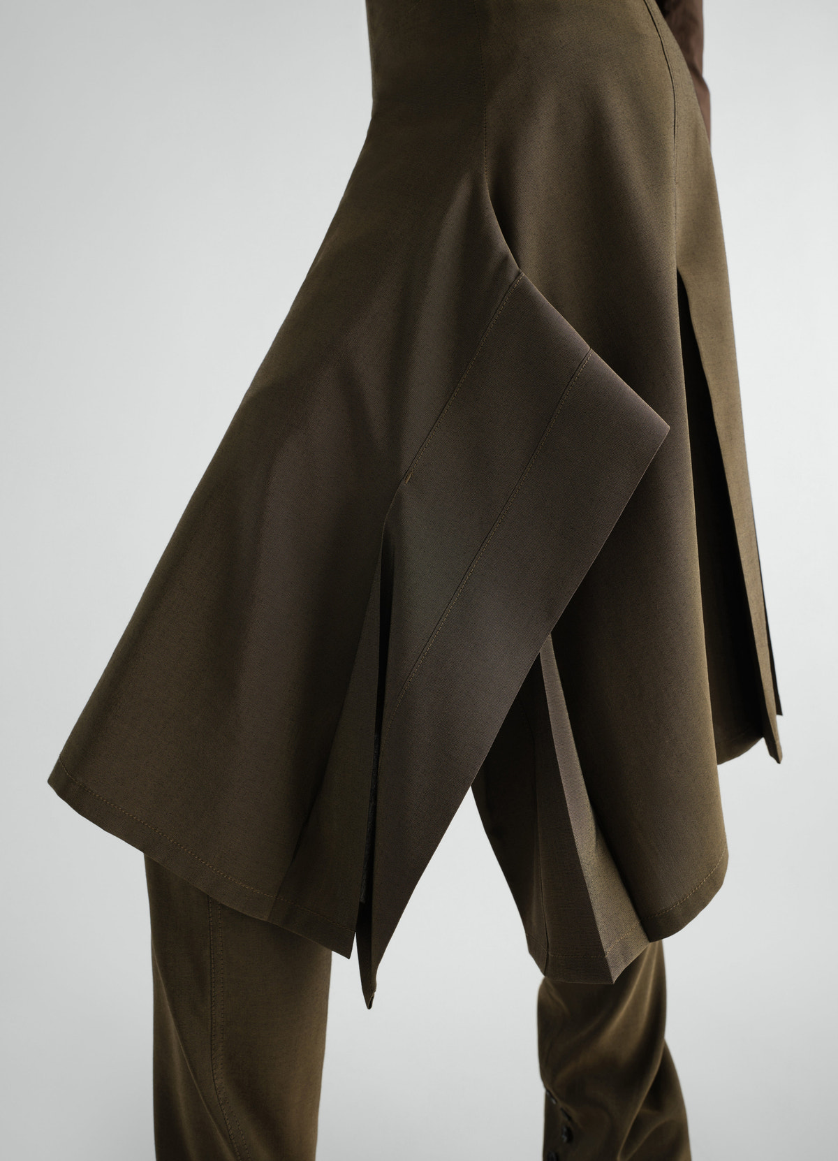 Pleated brown wool mohair skirt by lemaire worn by a model with visible layering and slits side view