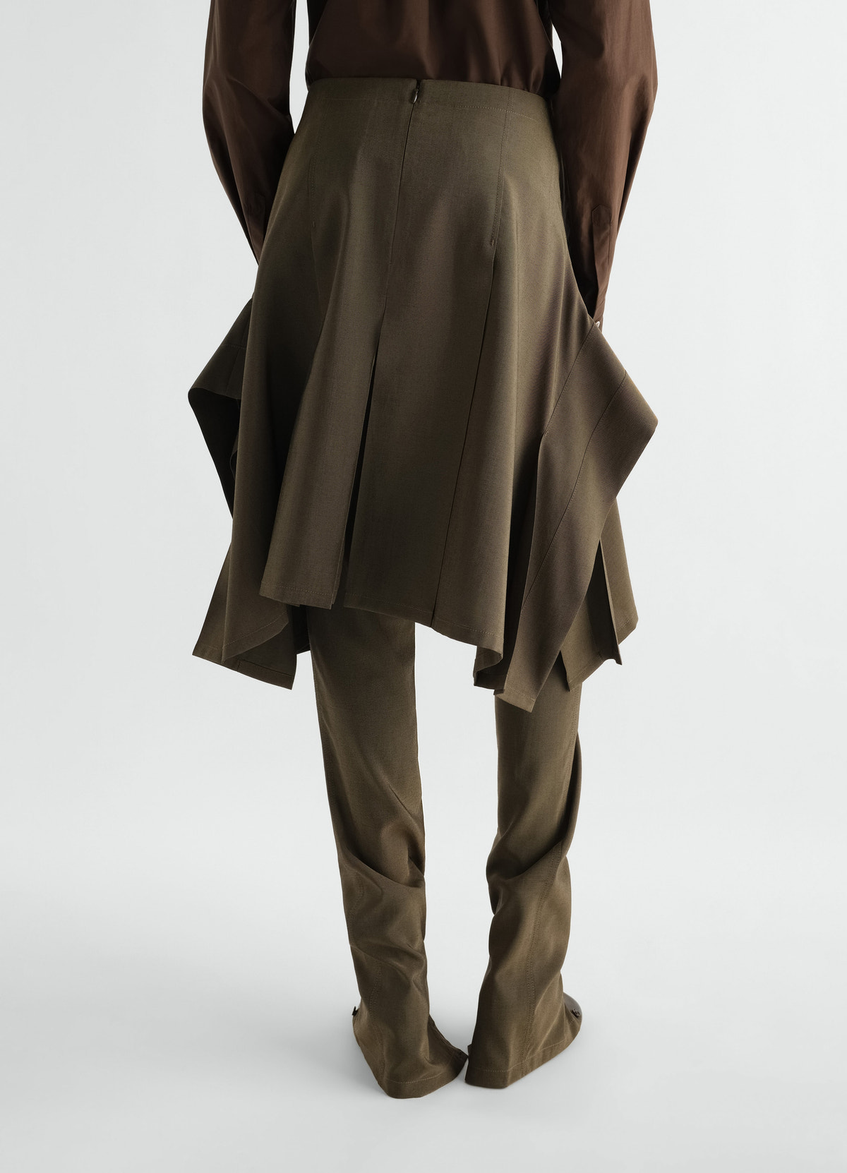Pleated olive wool and mohair skirt layered over pants worn by model back view lemaire