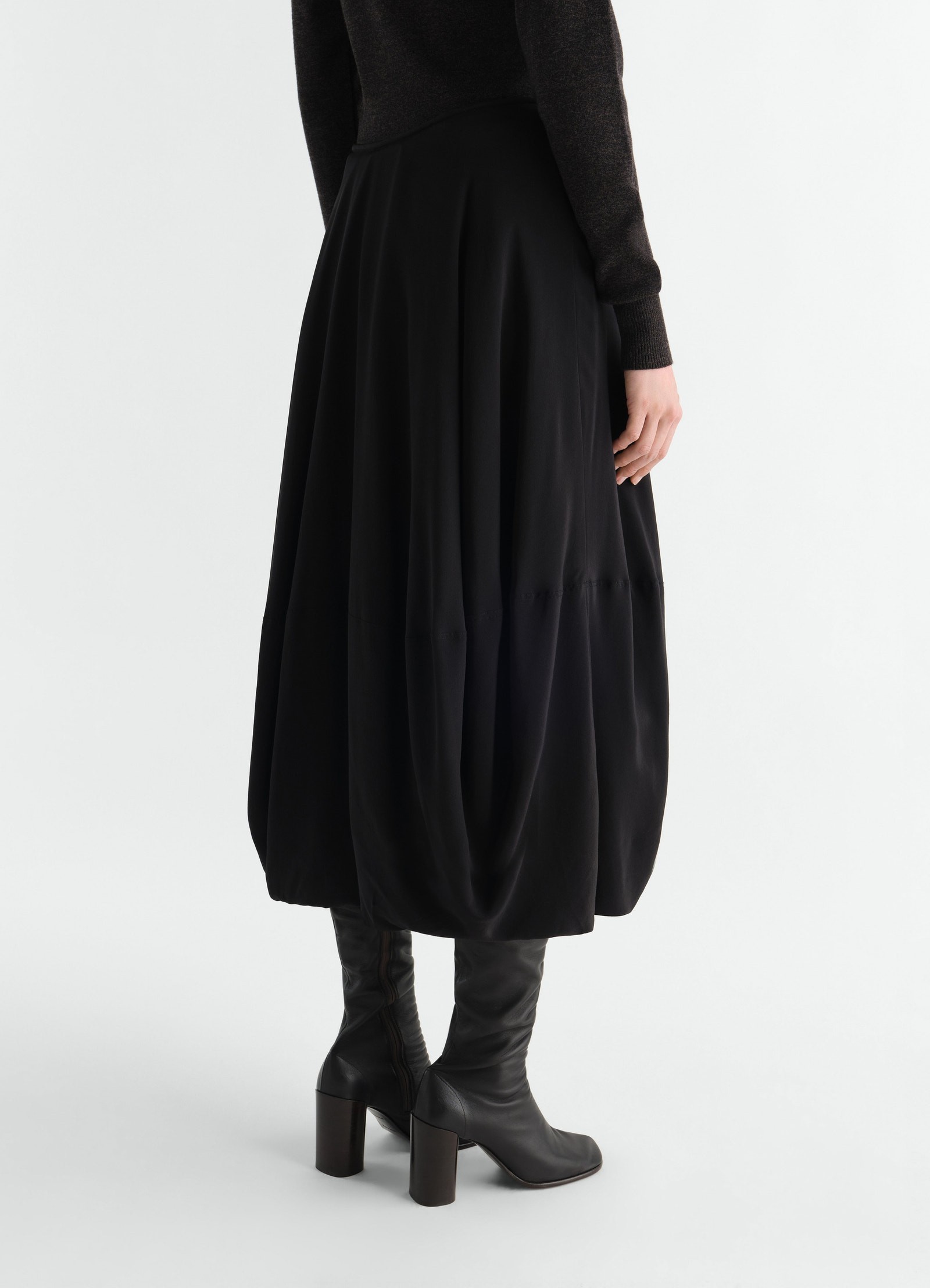 Balloon silk crepe de chine skirt in black by lemaire worn by a model back view with black boots