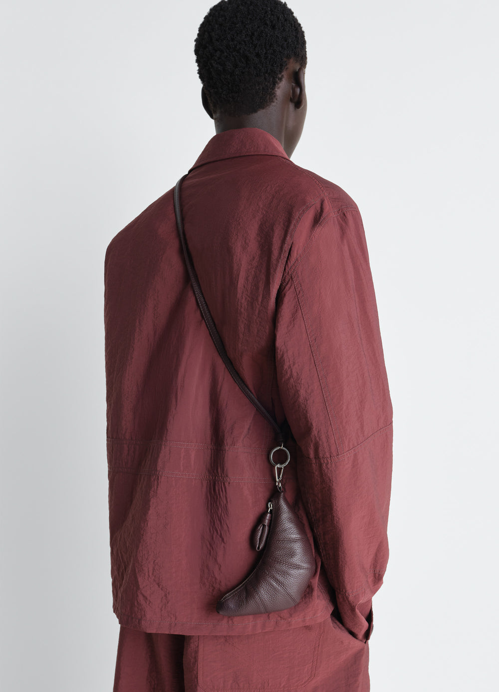 Crossbody Croissant Coin Purse in Grained Leather, model shot, back view crossbody worn on model