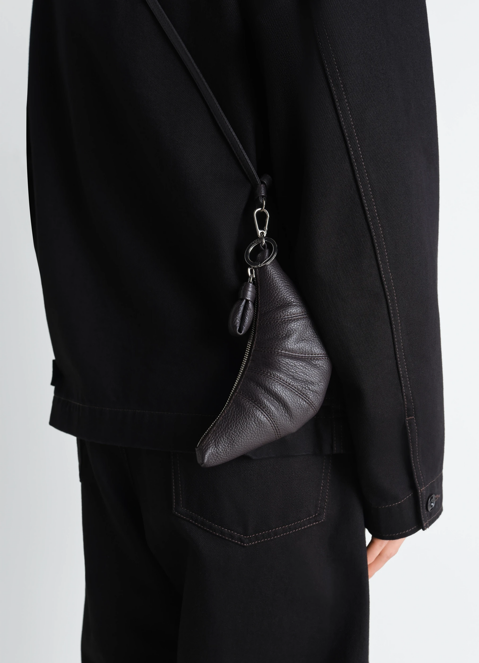Cross-body croissant coin purse in grained leather, model shot, side view on shoulder by model
