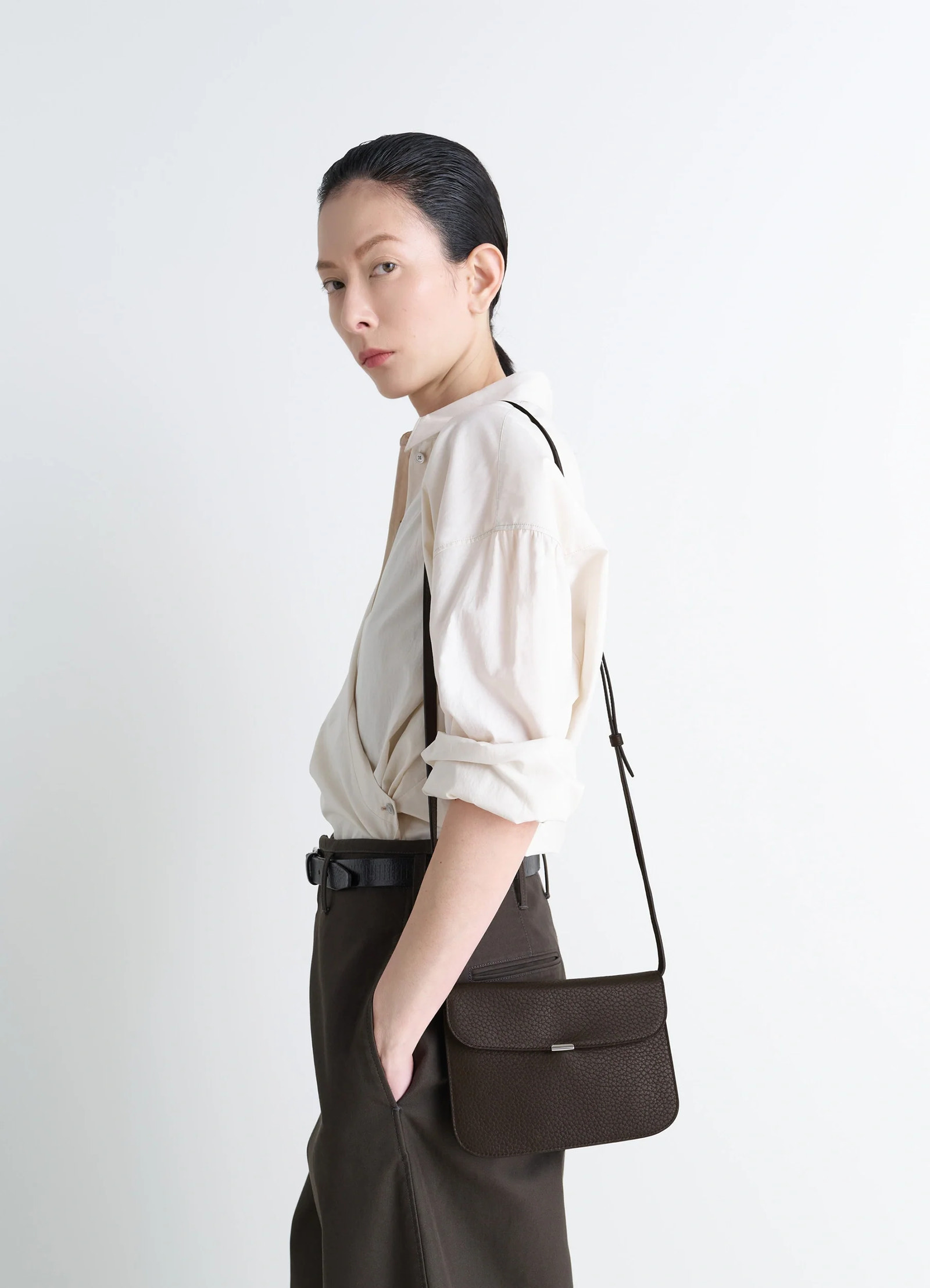 Soft tab wallet on strap in black leather, model shot, side view over-the-shoulder