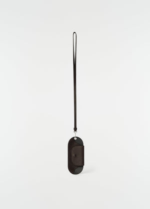 Glasses case in dark brown glossy vegetable-tanned leather with strap by lemaire front on white background