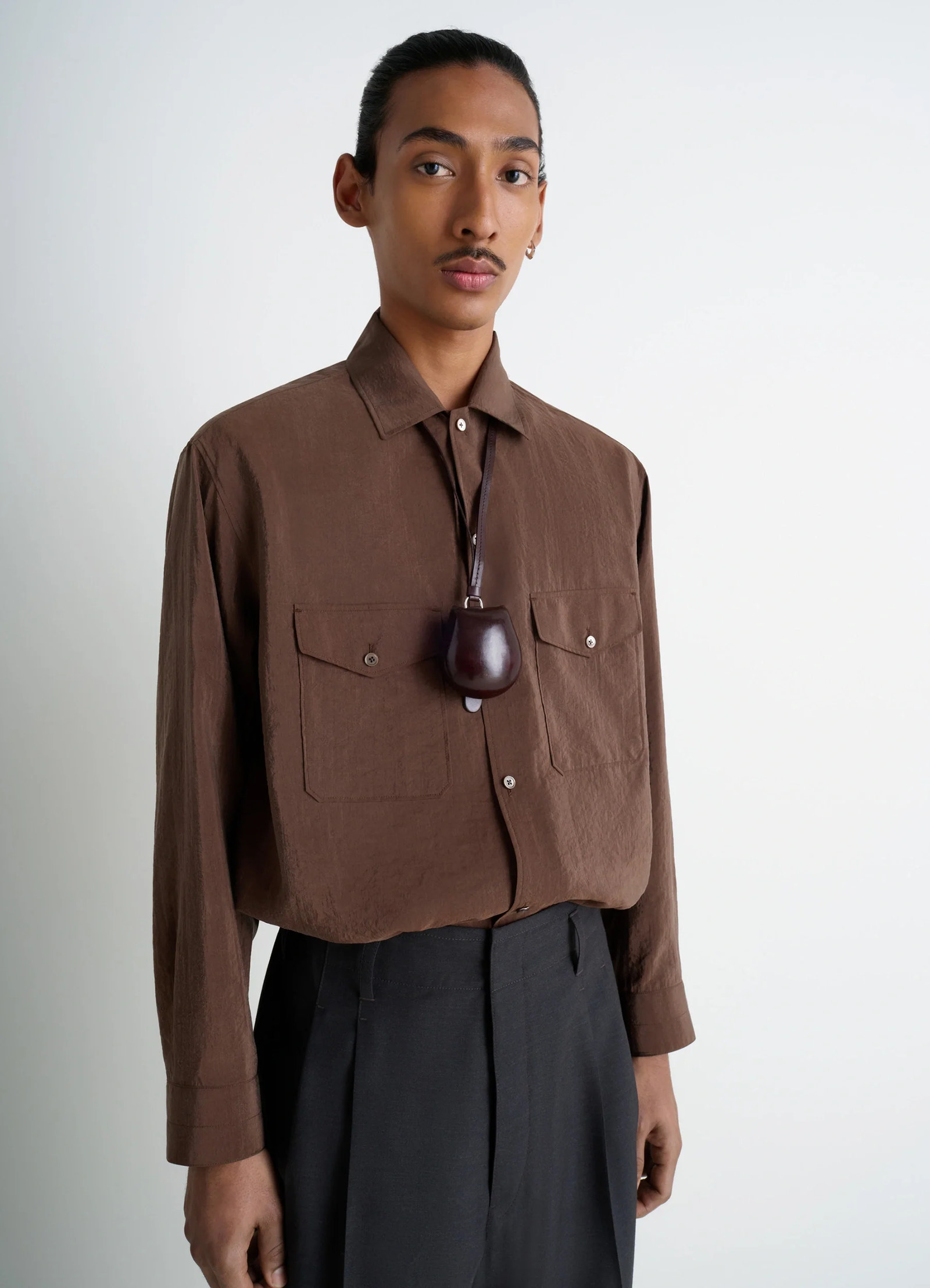 Carlos castanet coin purse necklace in molded vegetable-tanned leather, model shot, side view worn around neck