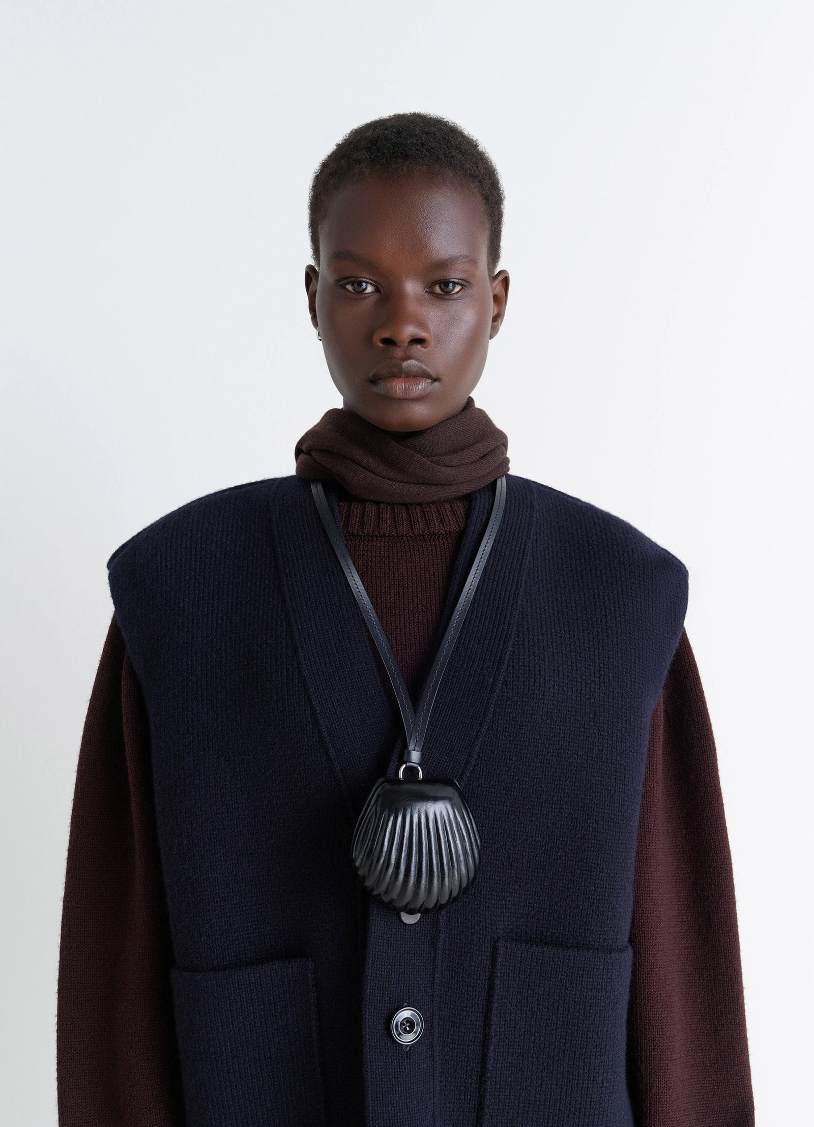 Carlos shell coin purse necklace in black vegetable-tanned leather, model shot, top view over dark sweater