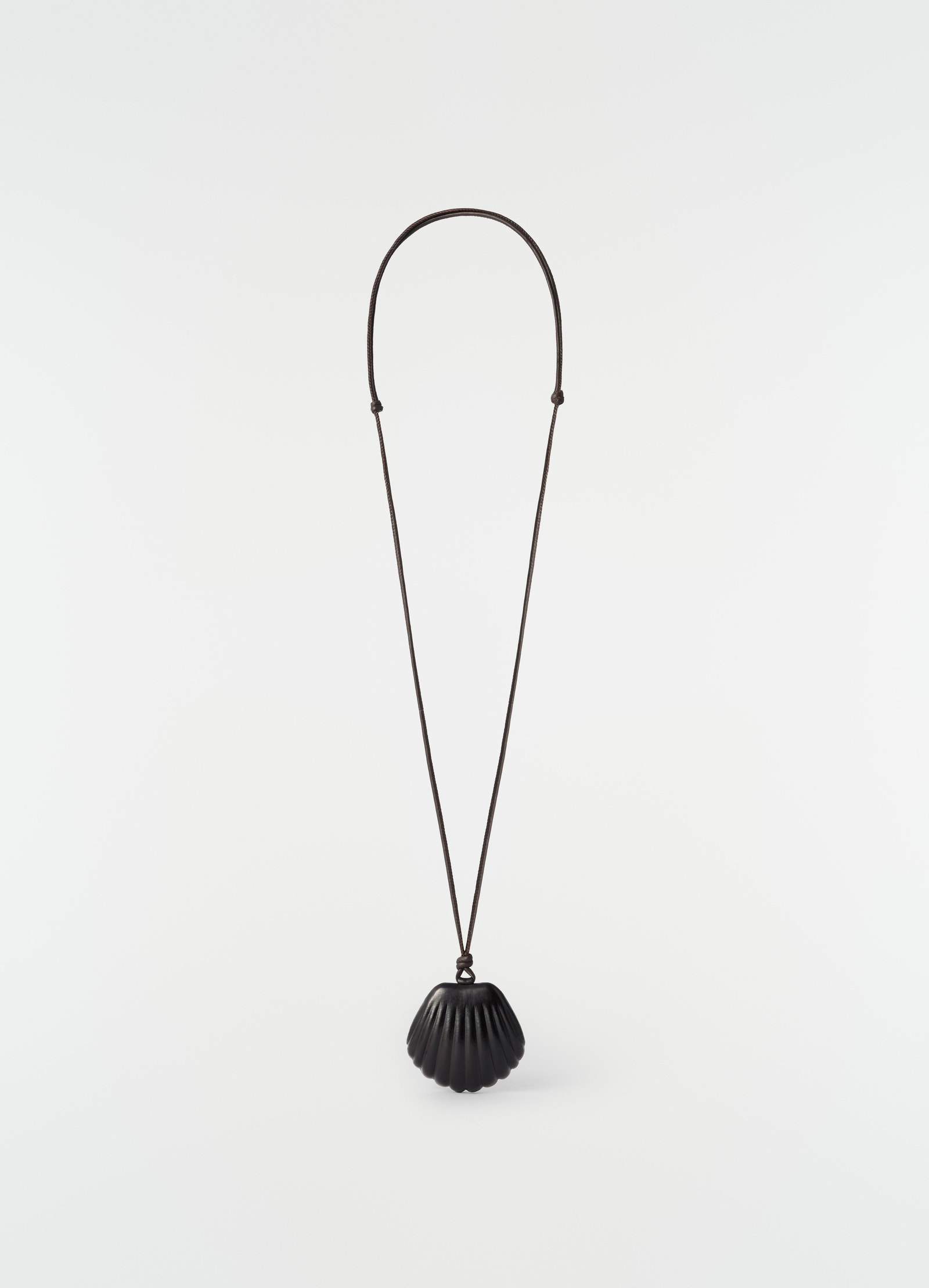 Shell mirror pendant in black patinated calfskin on long cord by lemaire on plain white background