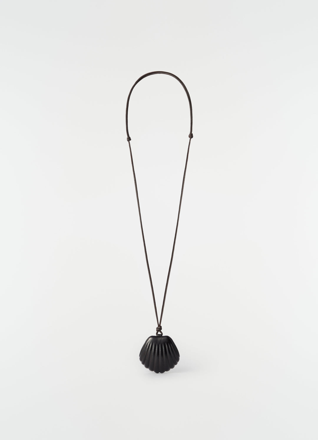 Shell mirror pendant in black patinated calfskin on long cord by LEMAIRE on plain white background