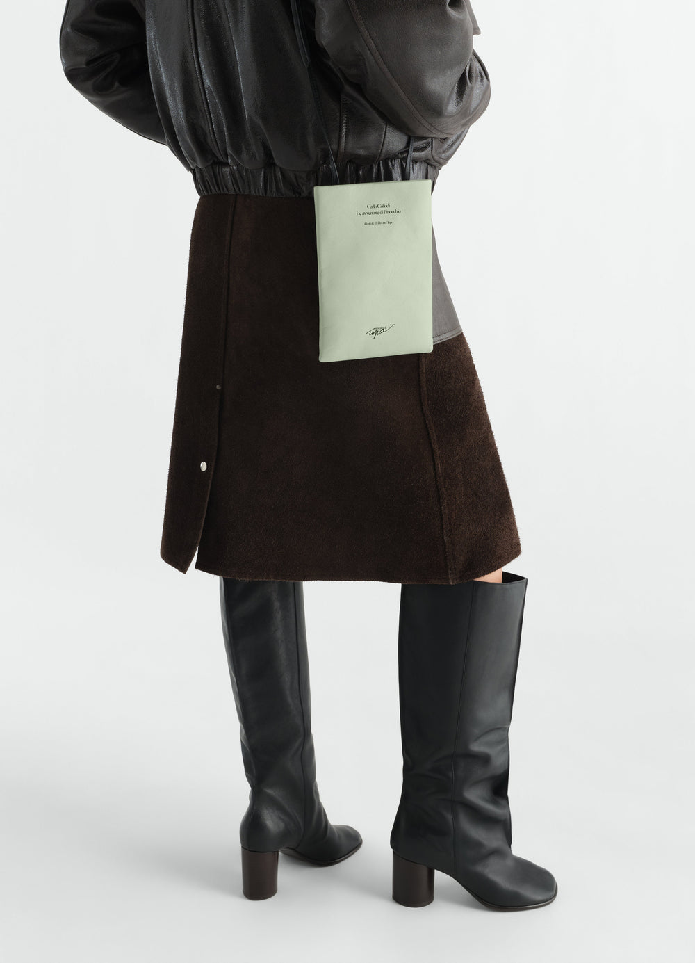 Medium Book Pouch in printed light green nappa leather by LEMAIRE worn by model with dark skirt and black boots side view
