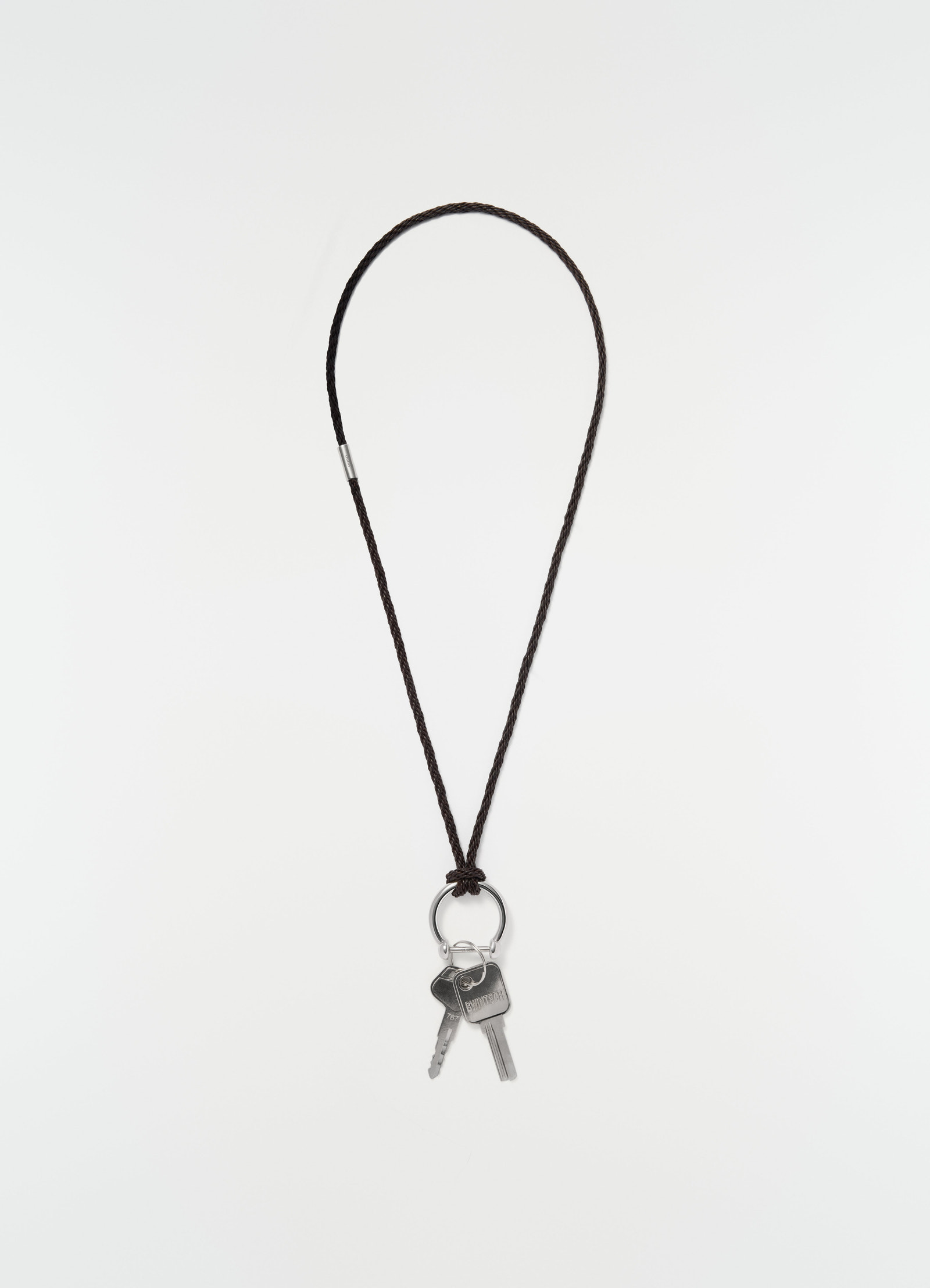 Keyring necklace with brown braided recycled leather cord and silver keys by lemaire on plain white background