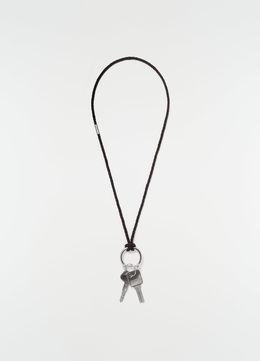 Keyring necklace with brown braided recycled leather cord and silver keys by LEMAIRE on plain white background