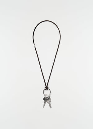 Keyring necklace with brown braided recycled leather cord and silver keys by lemaire on plain white background