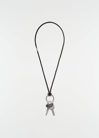 Keyring necklace with brown braided recycled leather cord and silver keys by LEMAIRE on plain white background
