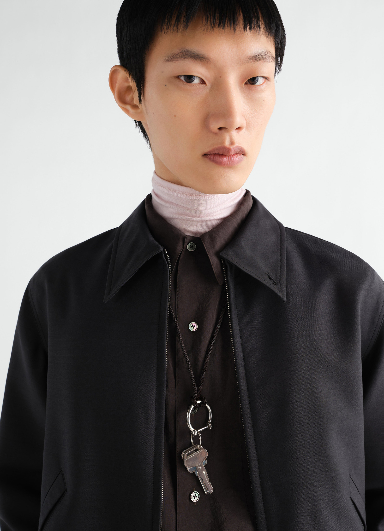 Keyring necklace with braided recycled leather cord in black worn by model lemaire close-up front