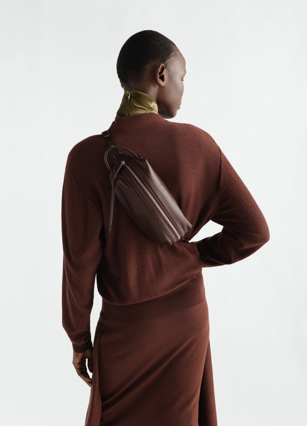 Sac care petit modèle en cuir d'agneau nappa, coloris marron, porté par un mannequin, fermeture zippée visible