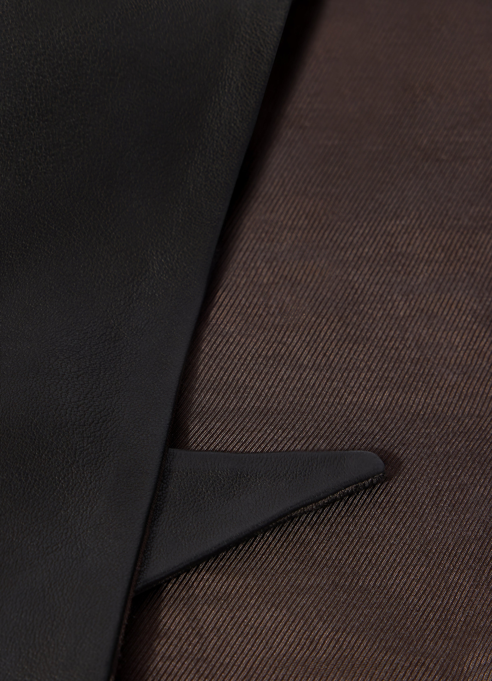 Leather triangle scarf in black by lemaire close-up detail on brown fabric background