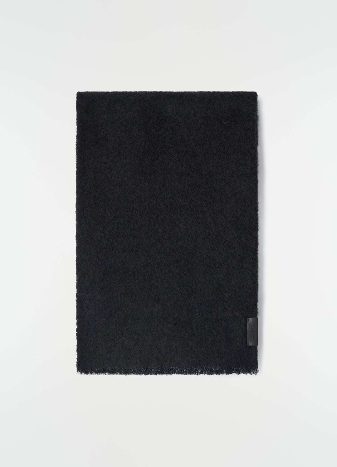 Fluffy black alpaca wool blend scarf by LEMAIRE laid flat with leather logo patch detail on white background