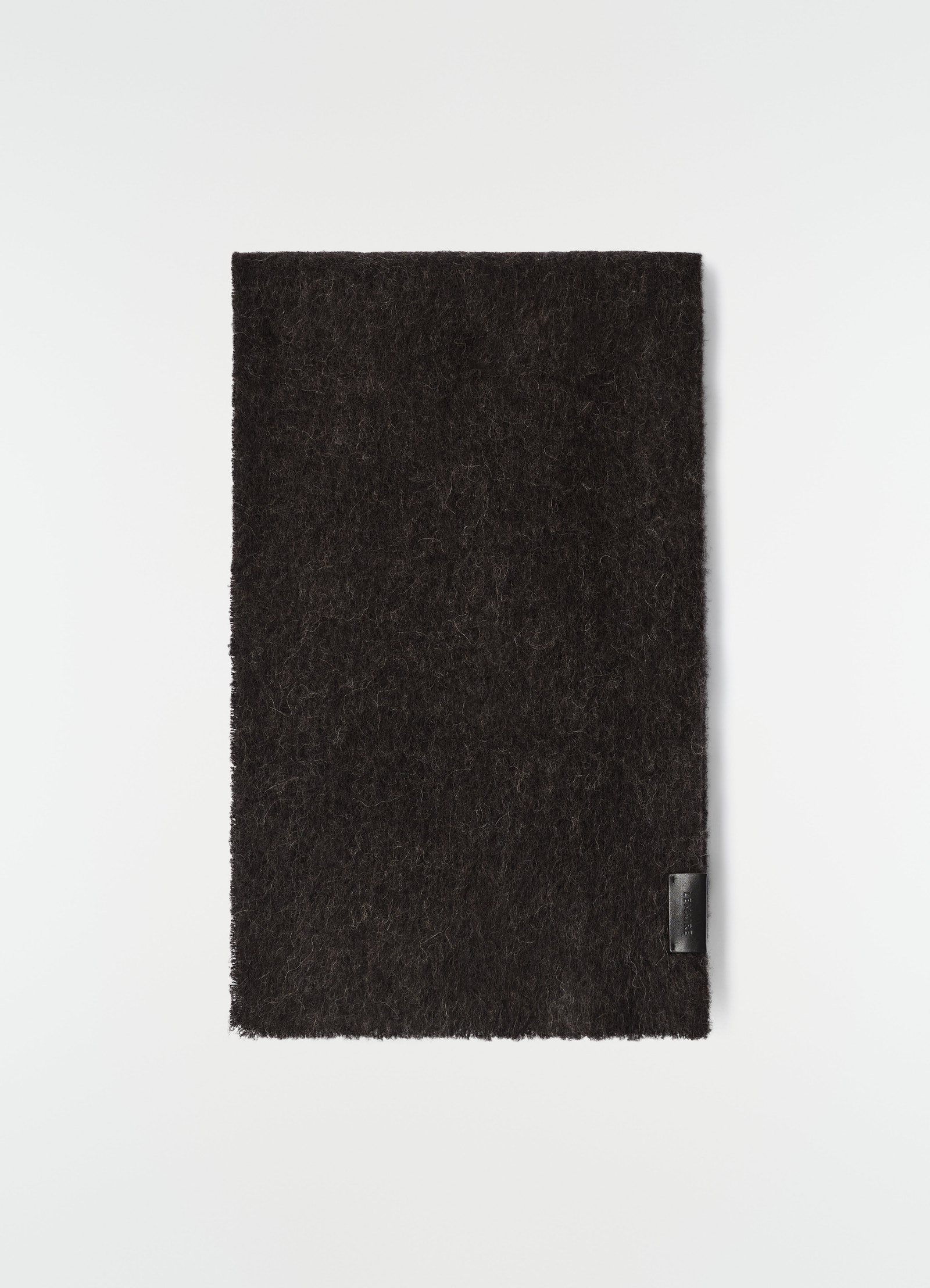Fluffy black alpaca wool blend scarf by lemaire flat lay with leather logo patch on plain white background